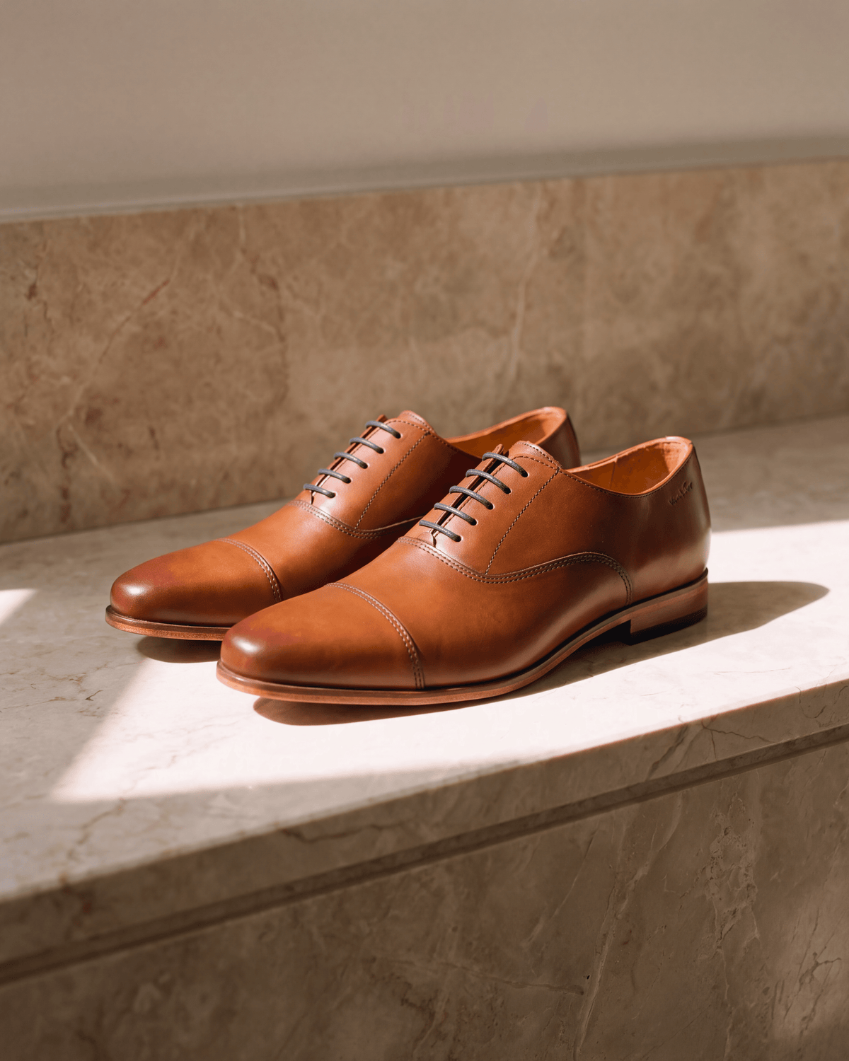 Cognac gladleren Rhodes veterschoen – het paar op warm marmer