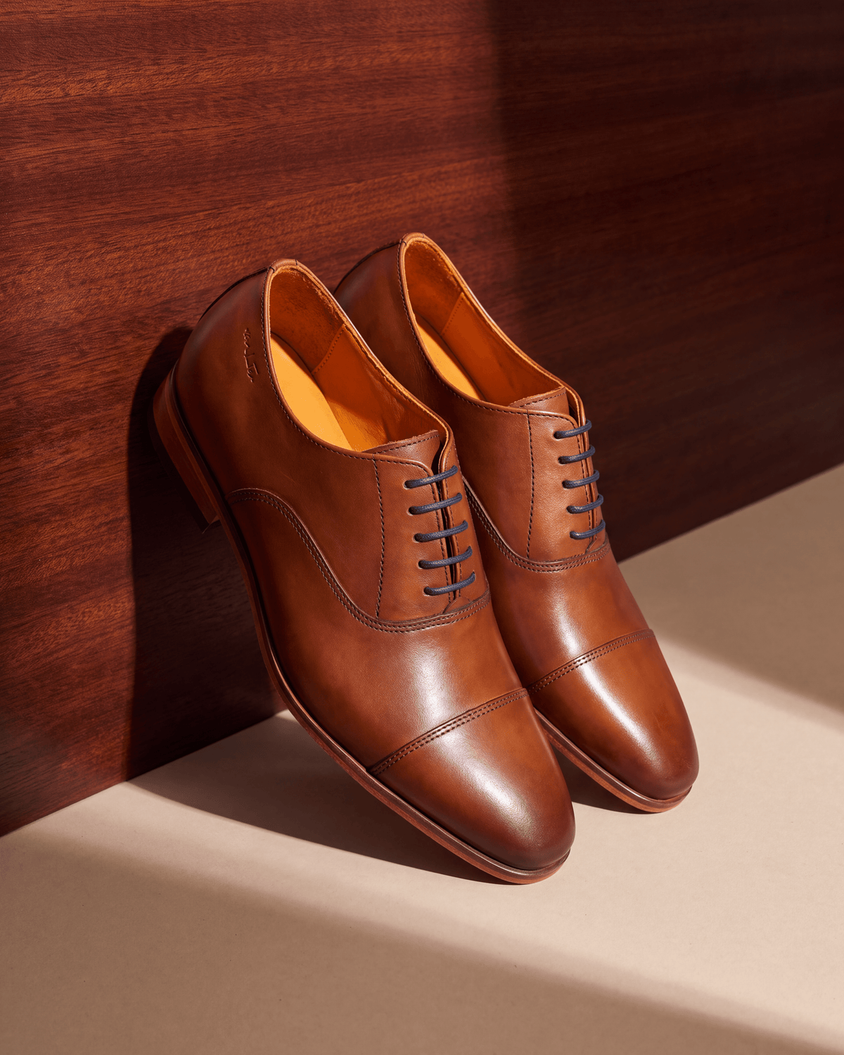 Cognac gladleren Rhodes veterschoen – het paar op hout en pleisterwerk