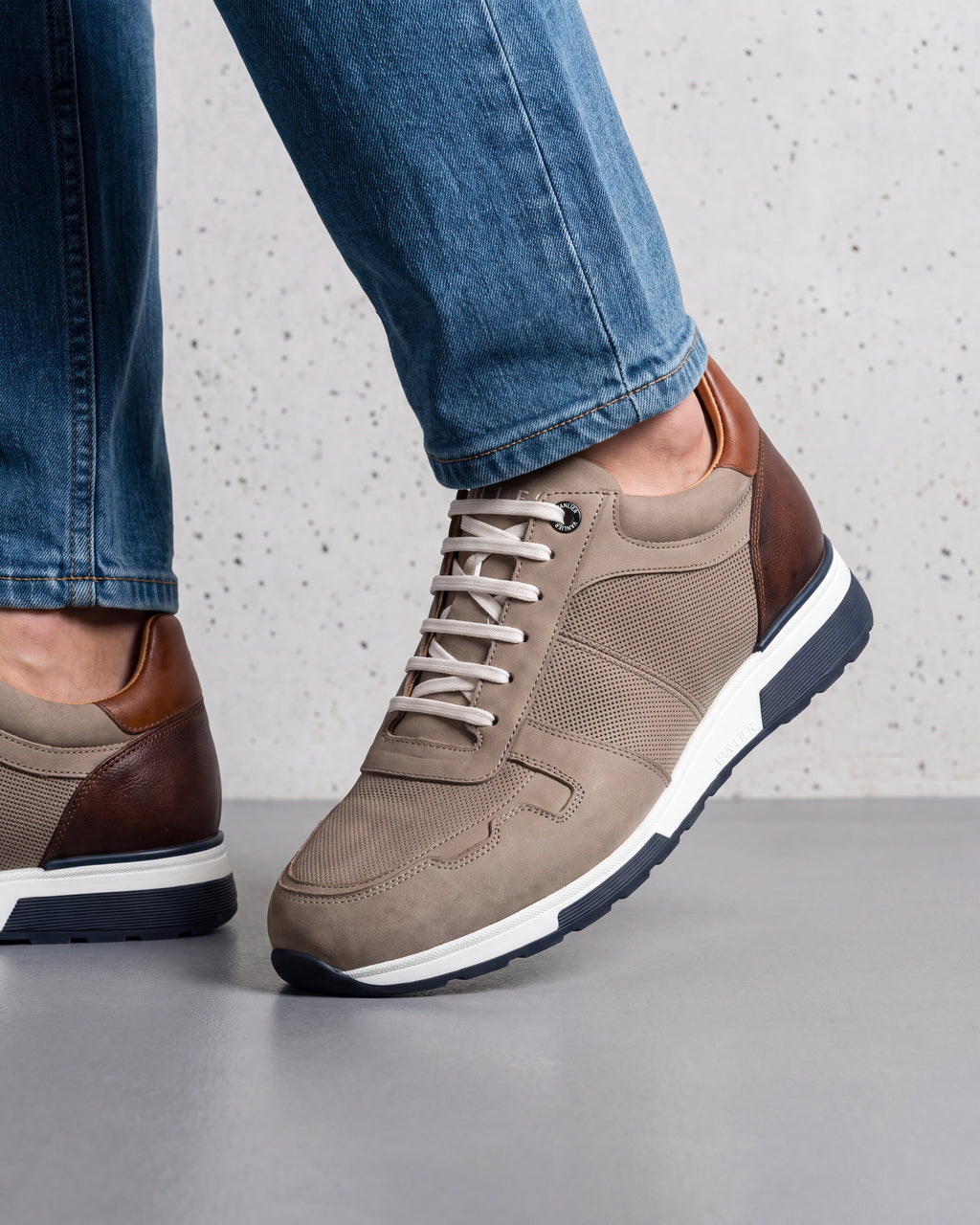 Taupe nubuck Positano sneaker – close-up van het paar in een betonnen atelier