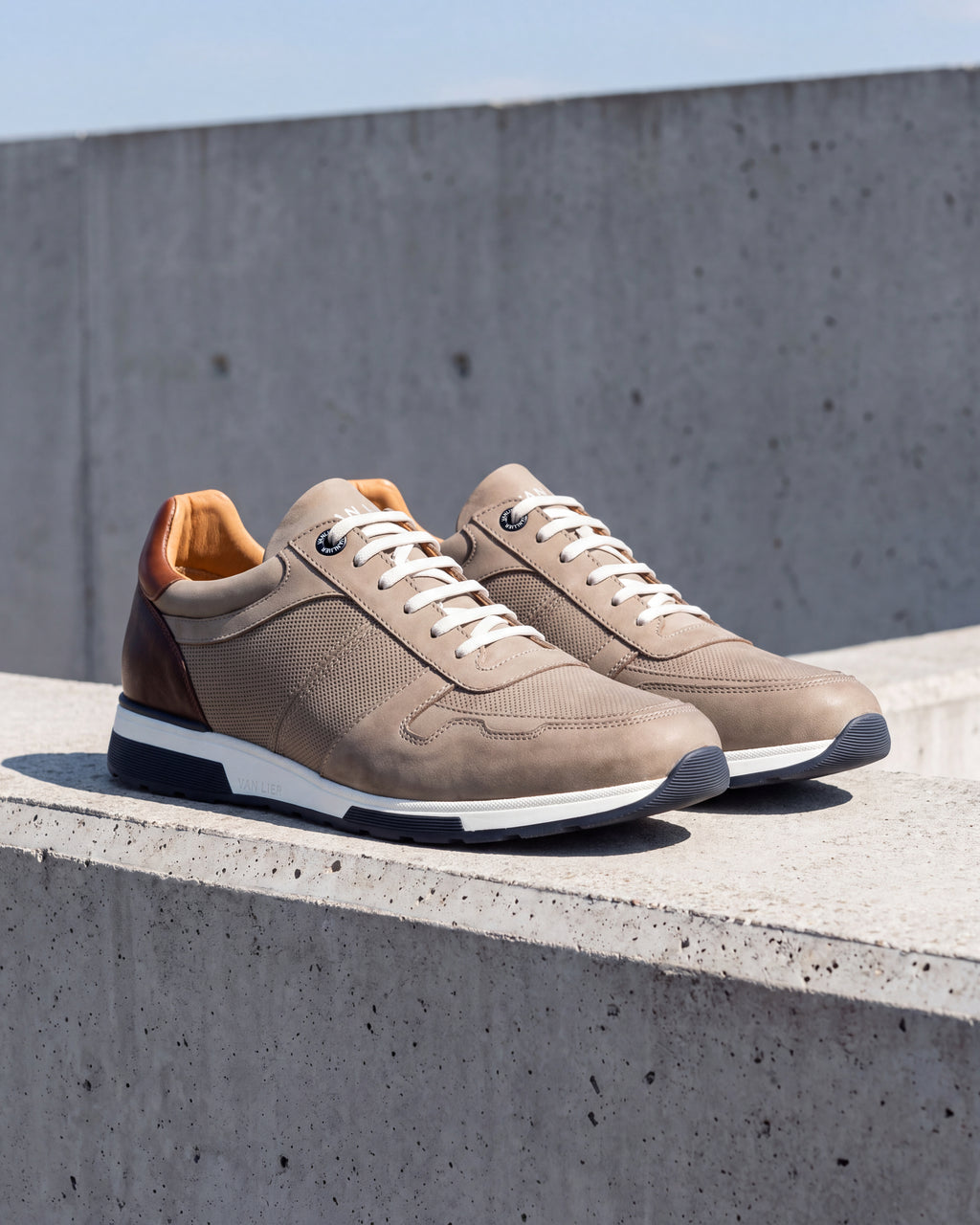 Taupe nubuck Positano sneaker – detail van het paar op ruw beton