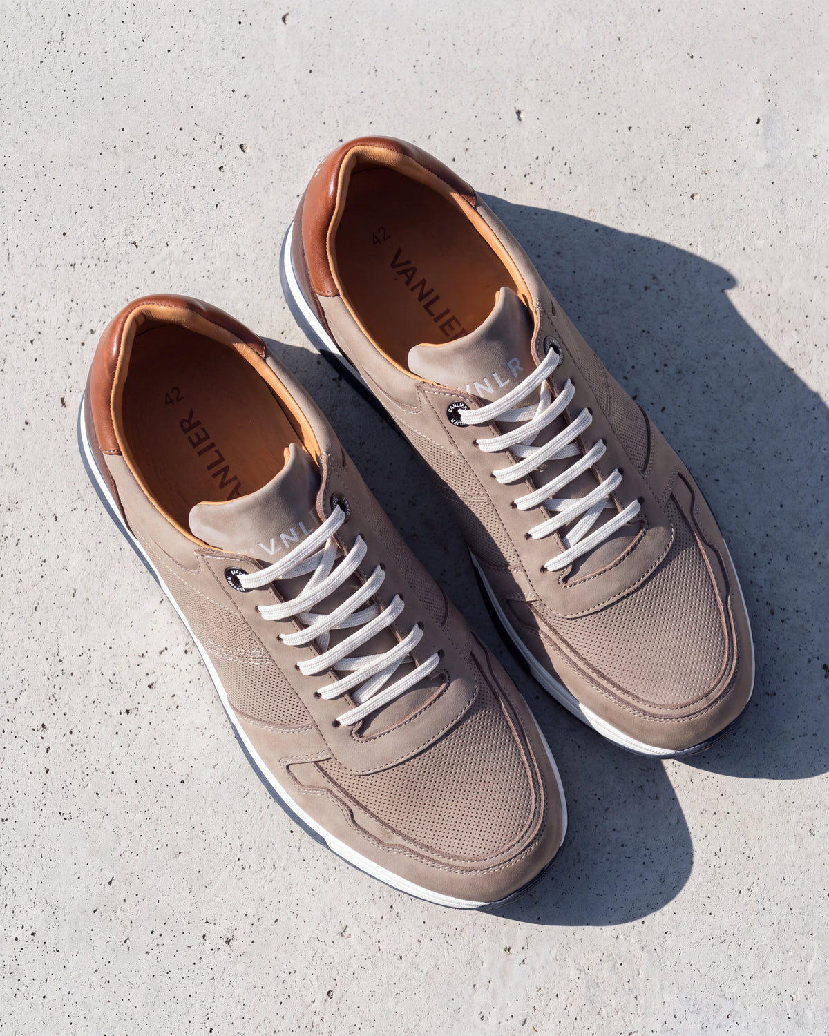 Taupe nubuck Positano sneaker – detail van het paar op ruw beton, andere hoek