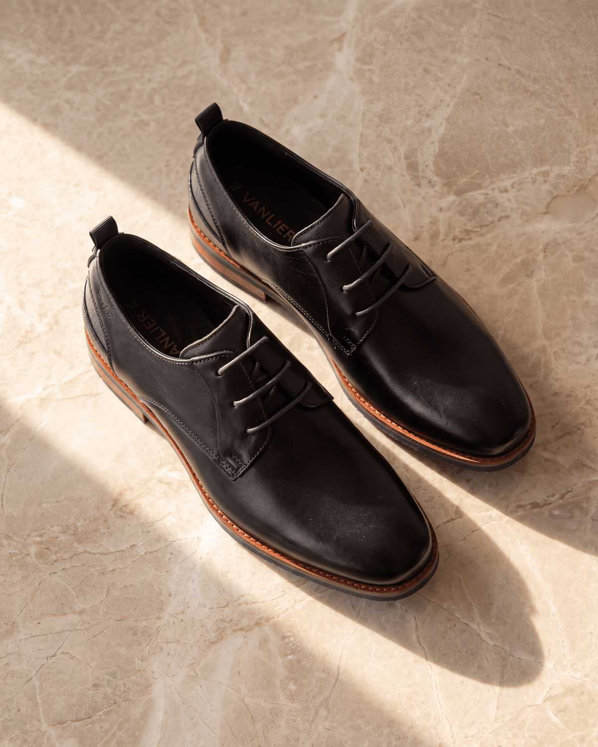Zwart gladleren Amalfi veterschoen – het paar op warm marmer