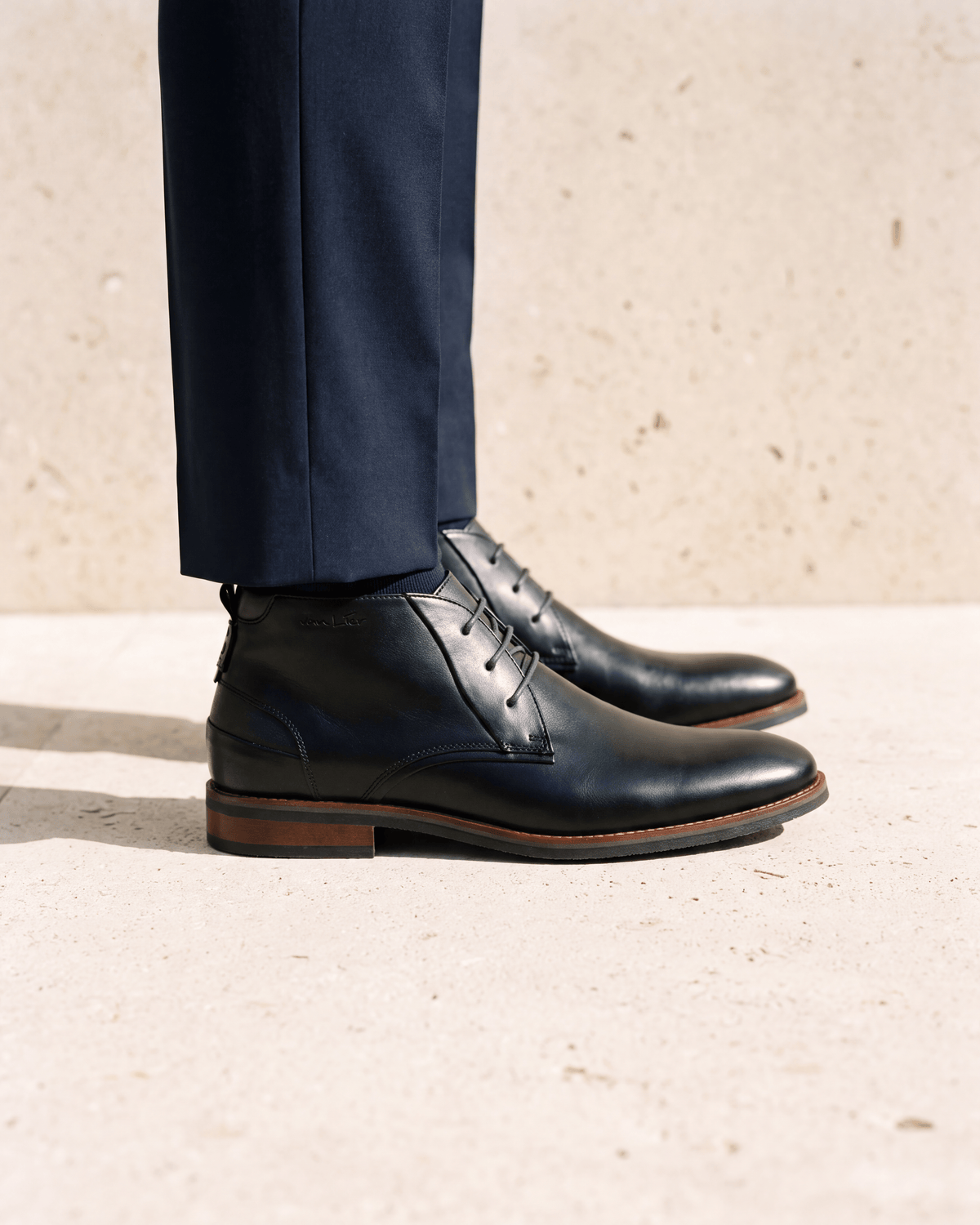 Zwart gladleren Amalfi halfhoge veterschoen – het paar op een kalkstenen vloer