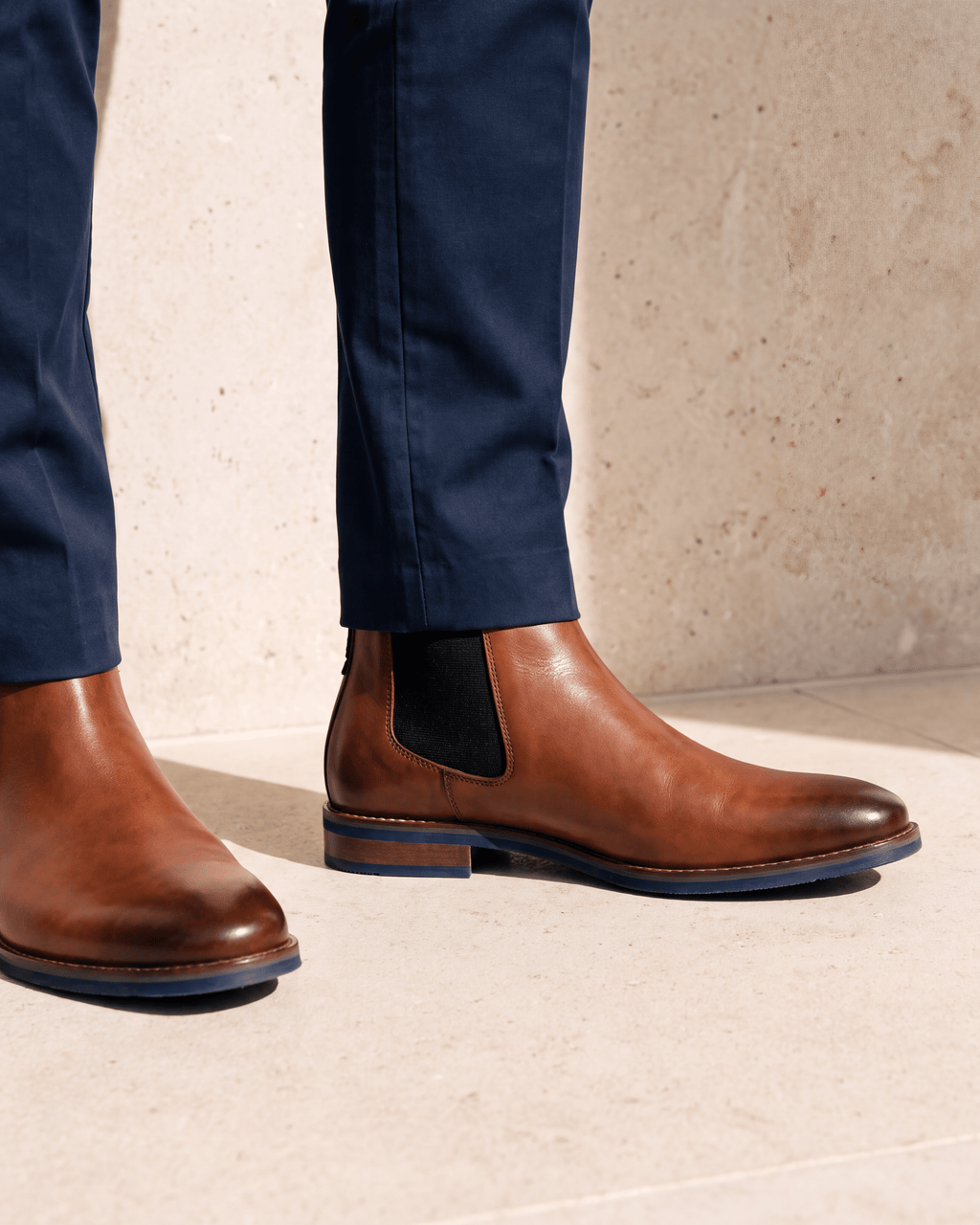 Cognac gladleren Amalfi chelsea boot – close-up van het paar op een kalkstenen vloer, derde hoek