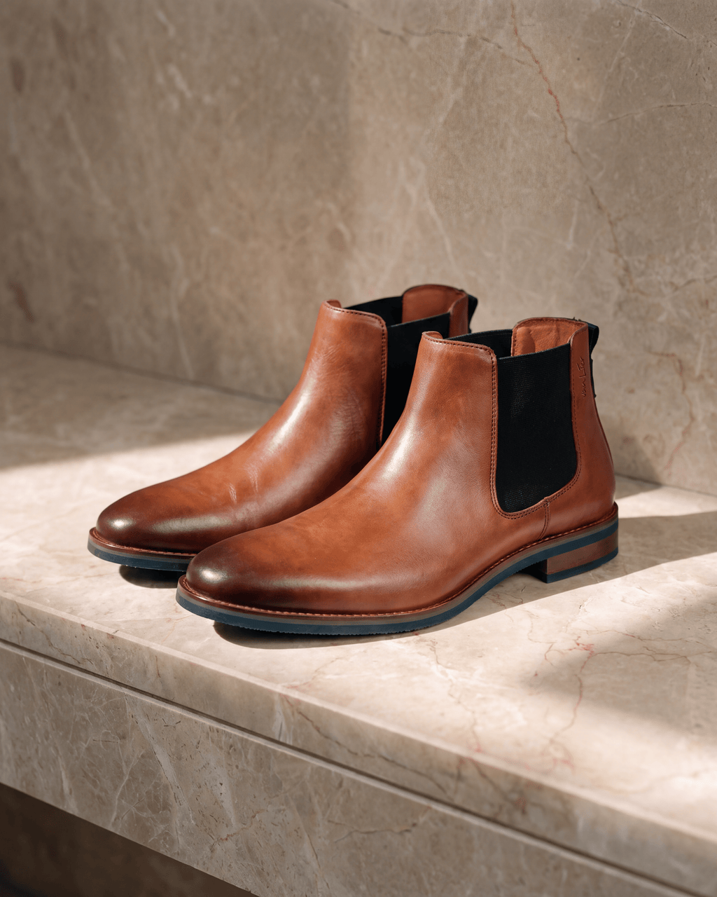 Cognac gladleren Amalfi chelsea boot – stilleven op warm marmer