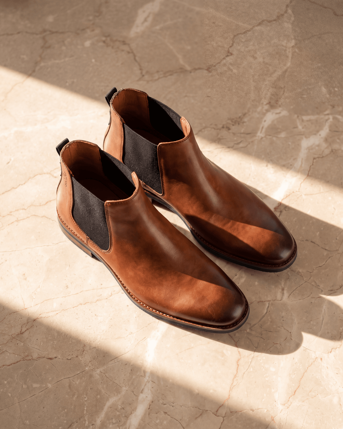 Cognac gladleren Amalfi chelsea boot – derde stilleven op warm marmer