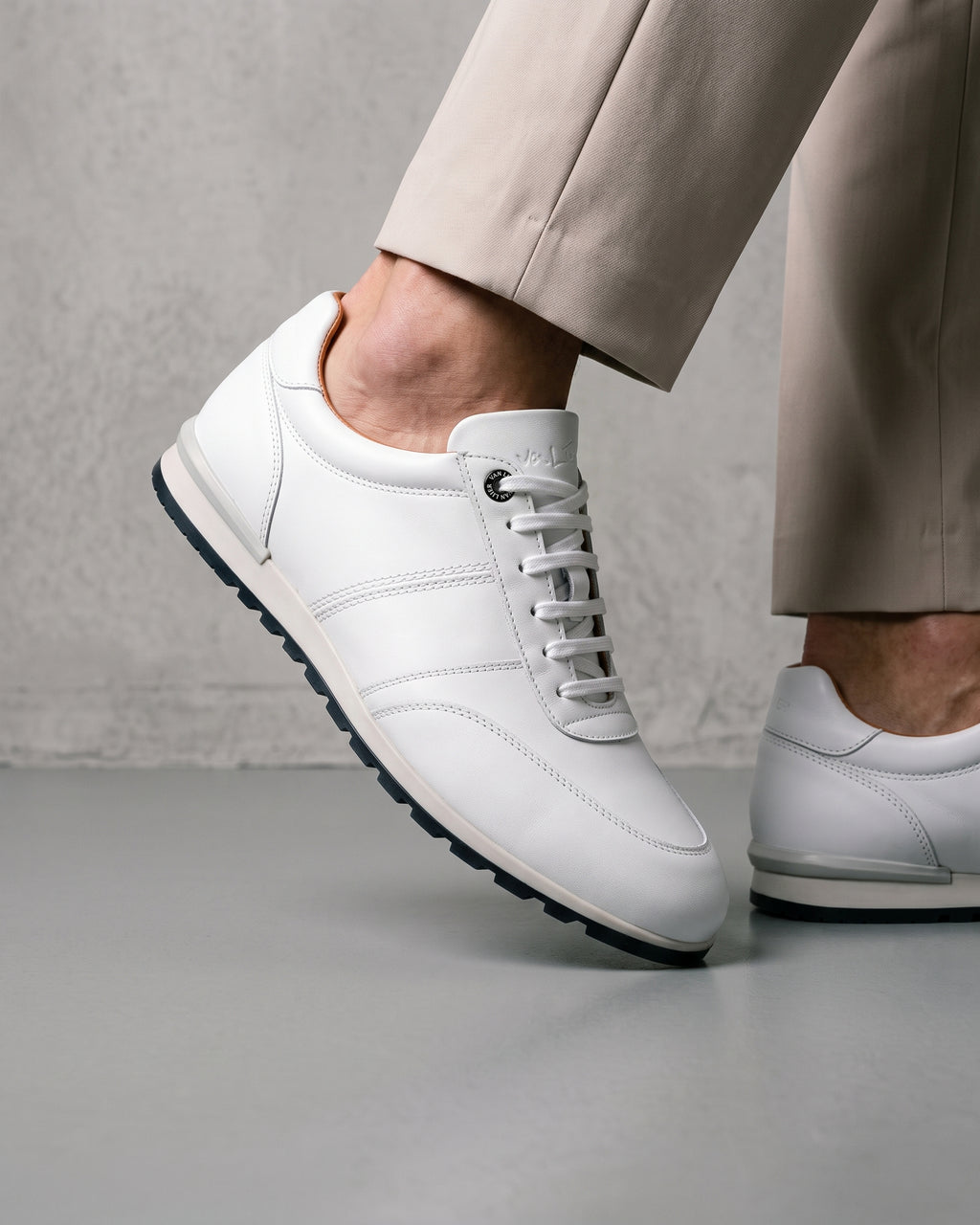 Wit gladleren Anzano sneaker – close-up van het paar in een betonnen atelier