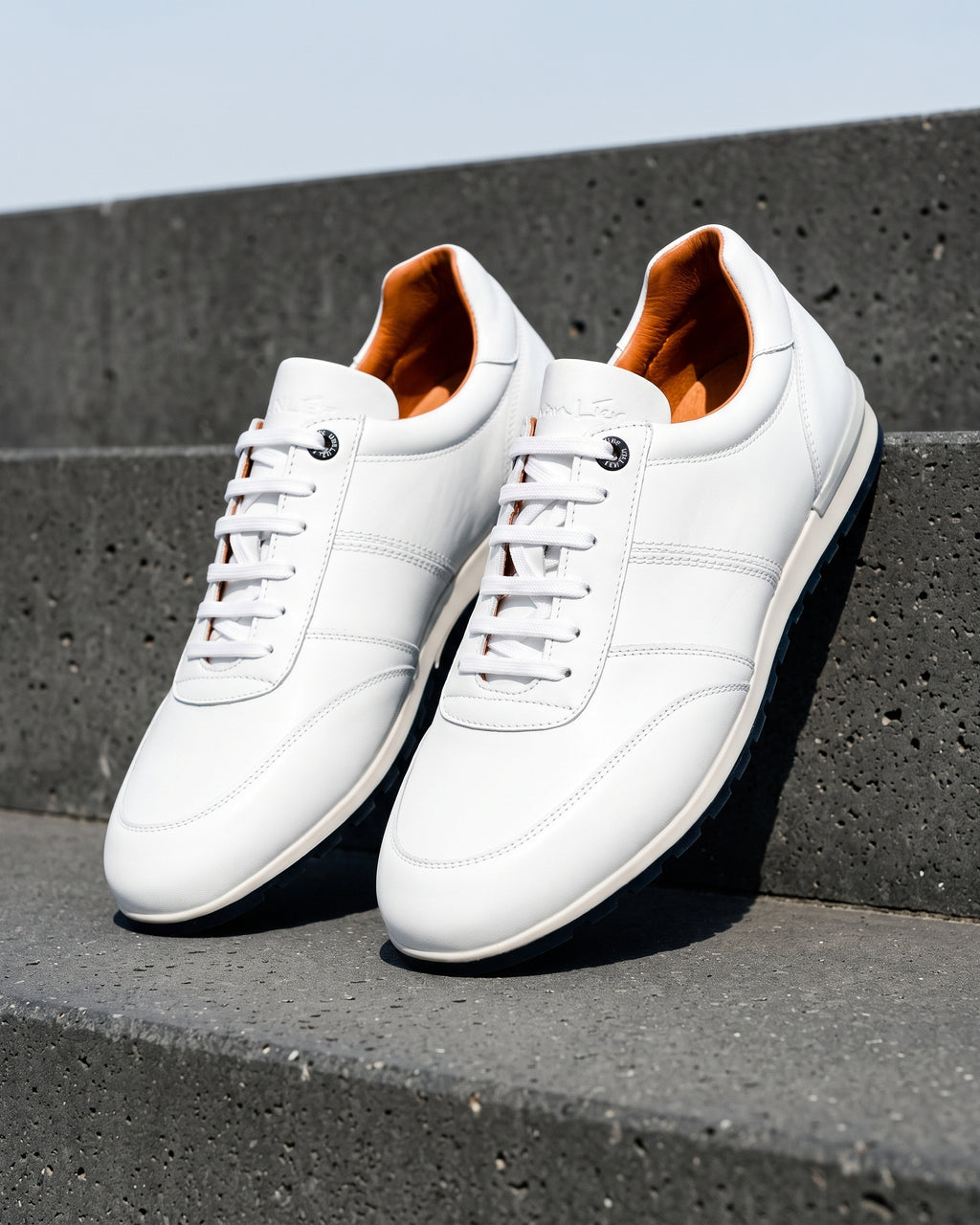 Wit gladleren Anzano sneaker – close-up van het paar op ruw beton