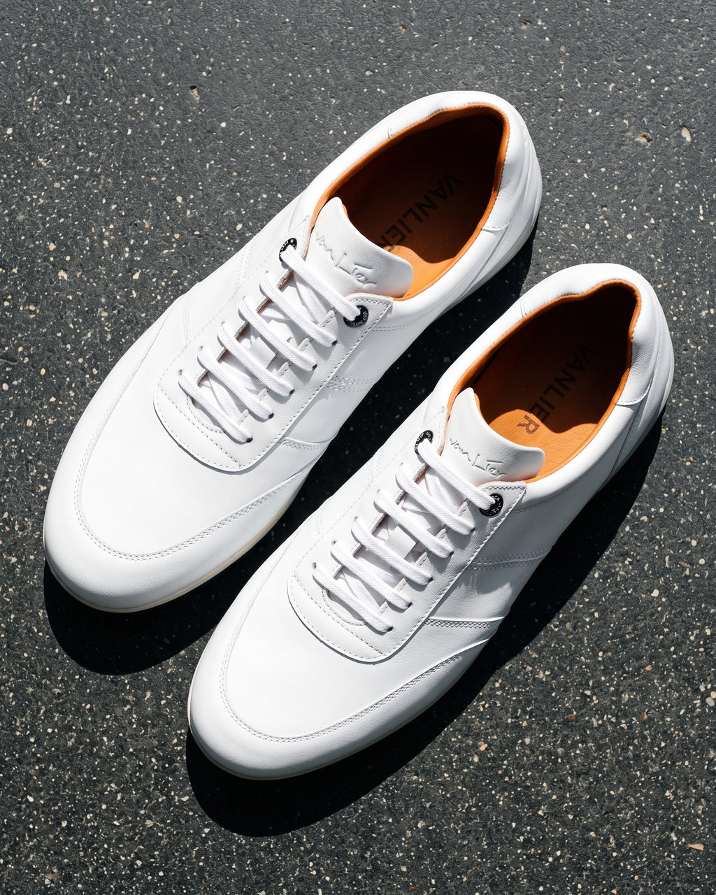 Wit gladleren Anzano sneaker – close-up van het paar op ruw beton