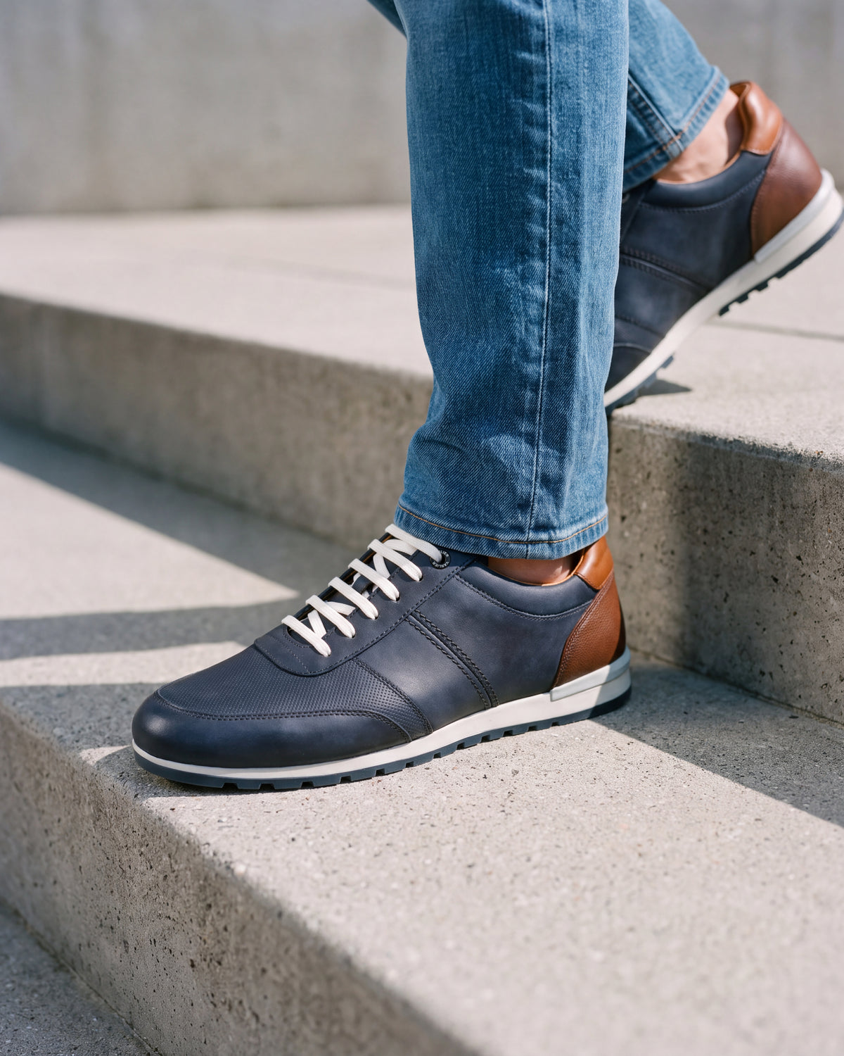 Navy blauw nubuck Anzano sneaker – close-up van het paar op een ruwe betonnen vloer