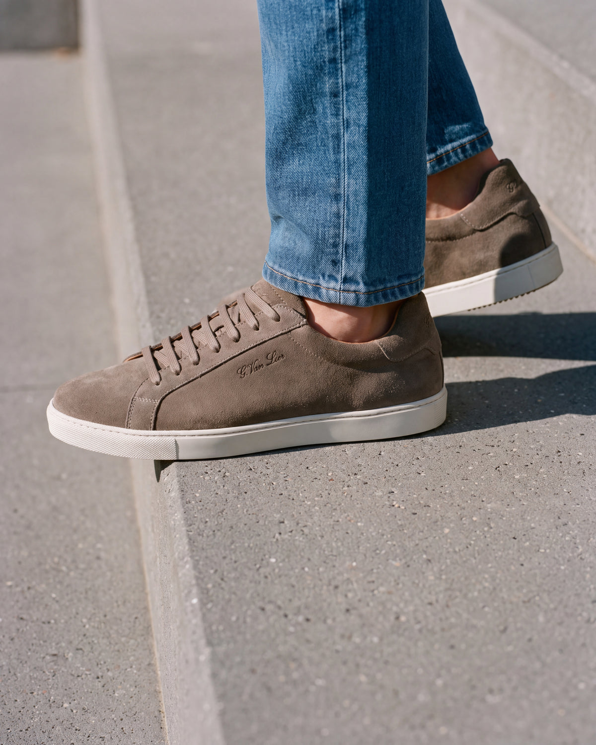 Taupe suède Napoli sneaker – close-up van het paar op een ruwe betonnen vloer
