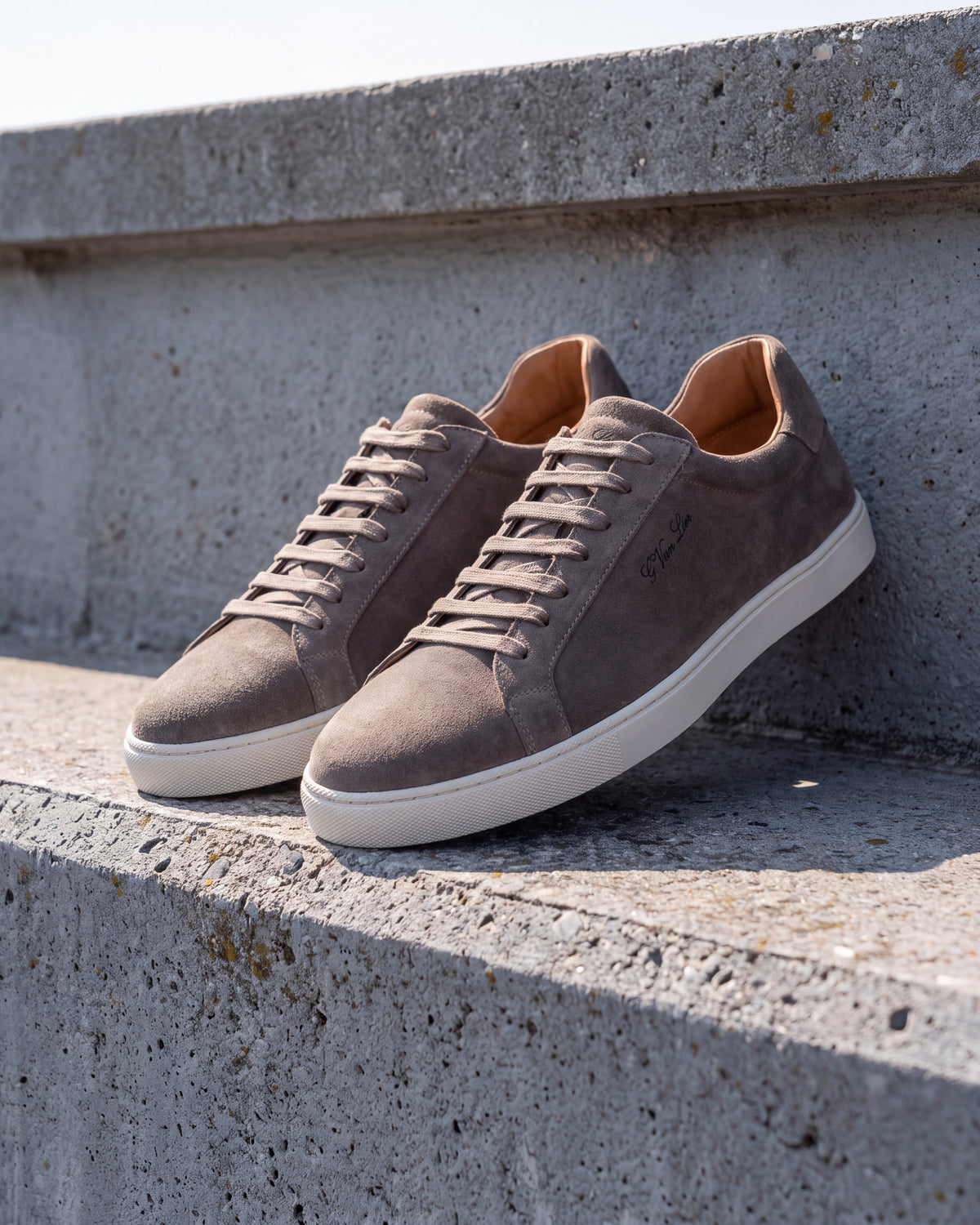 Taupe suède Napoli sneaker – detail van het paar op ruw beton