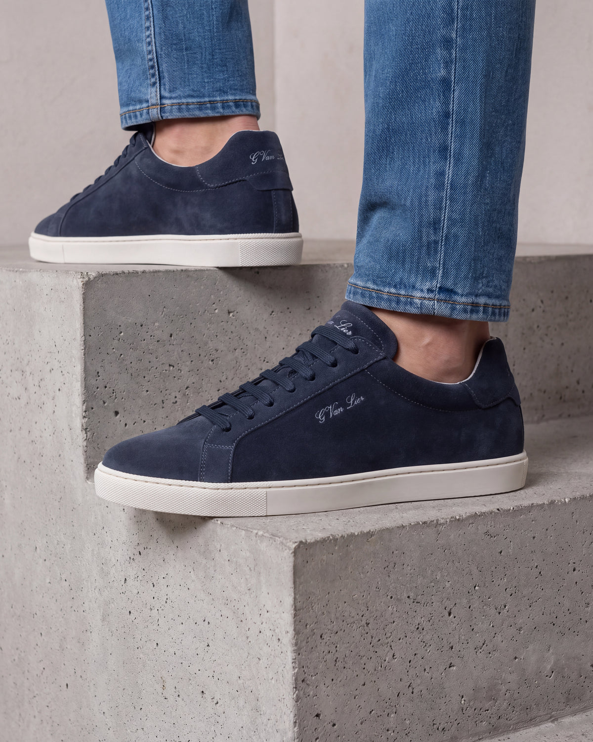 Navy blauw suède Napoli sneaker – close-up van het paar op een betonnen vloer in een atelier