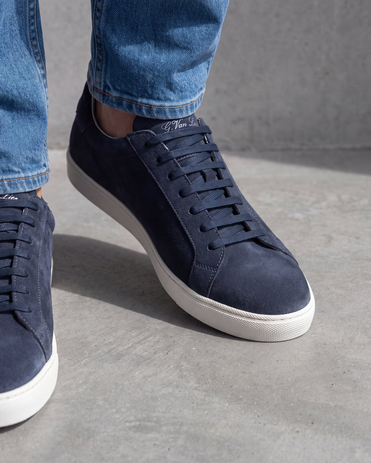Navy blauw suède Napoli sneaker – close-up van het paar op een ruwe betonnen vloer