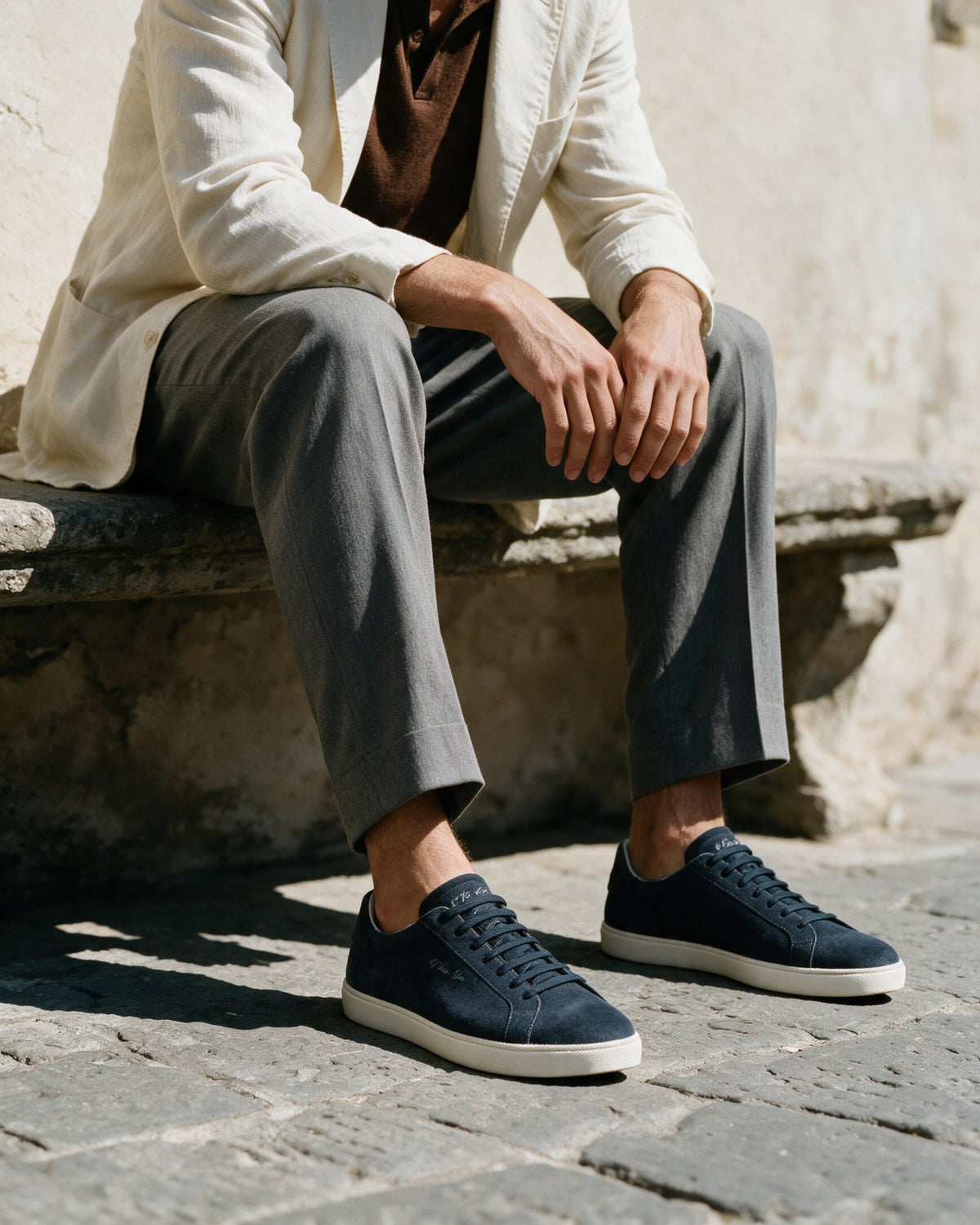 Navy blauw suède Napoli sneaker – lifestyle op een stenen bank