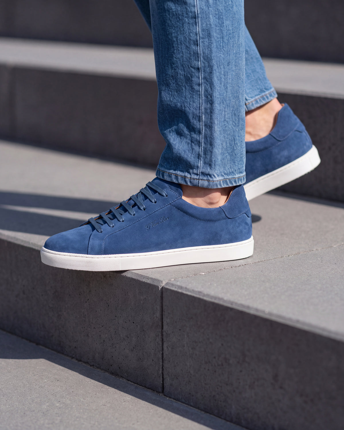 Blauw suède Napoli sneaker – close-up van het paar op een ruwe betonnen vloer