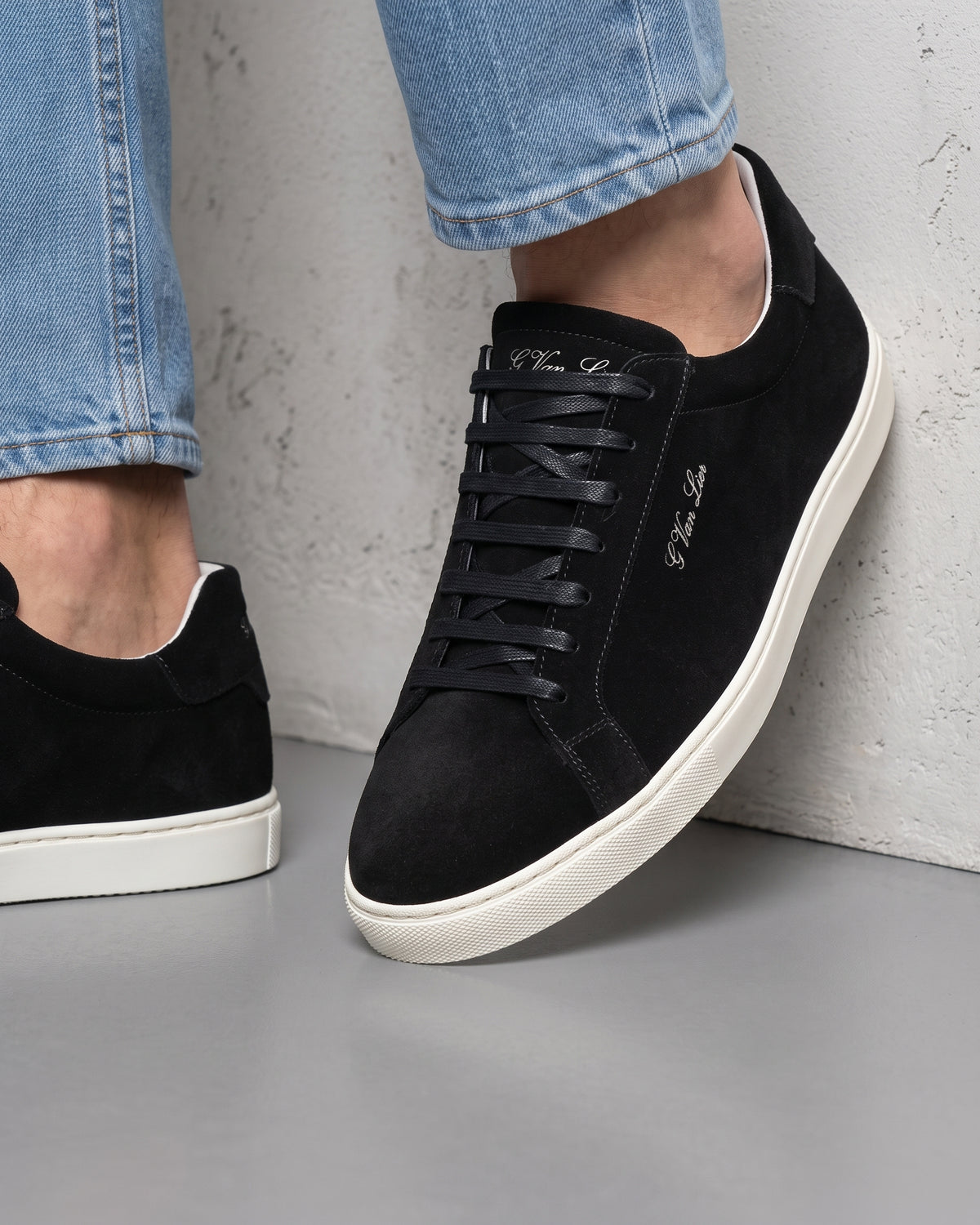 Zwart suède Napoli sneaker – close-up van het paar in een betonnen atelier