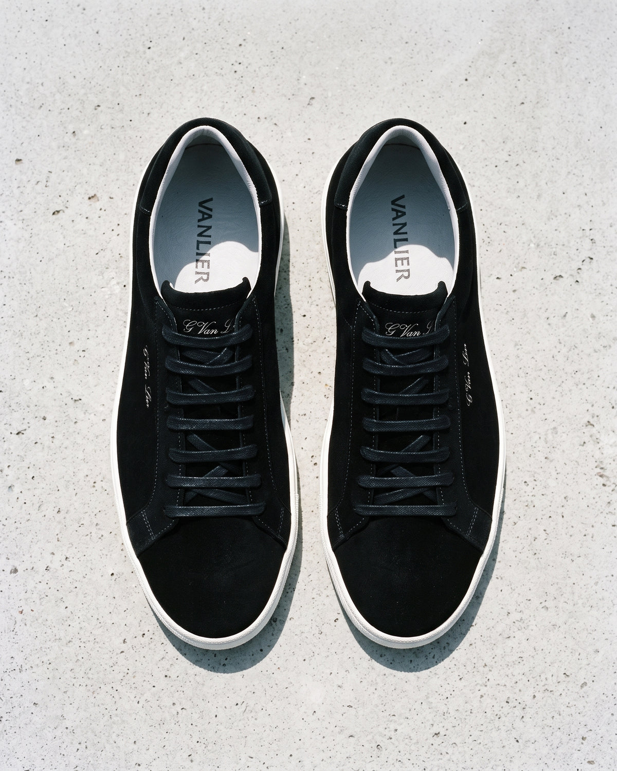 Zwart suède Napoli sneaker – close-up van het paar op ruw beton