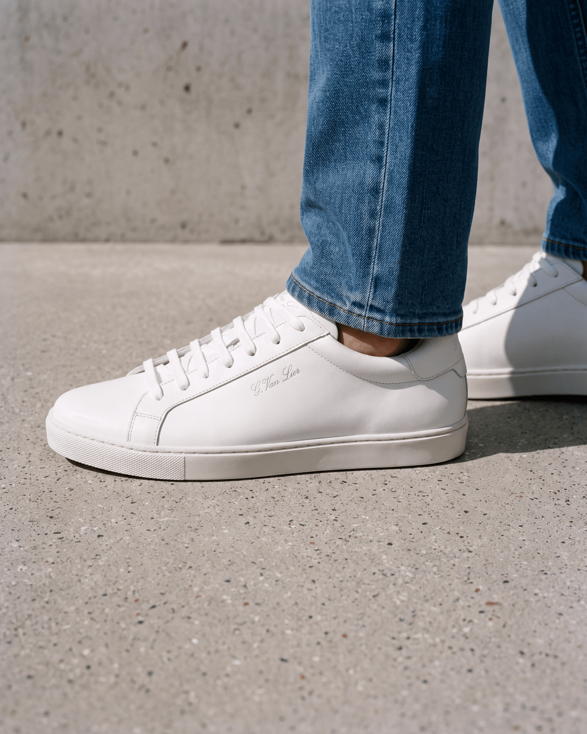 Wit gladleren Napoli sneaker – close-up van het paar op ruw beton