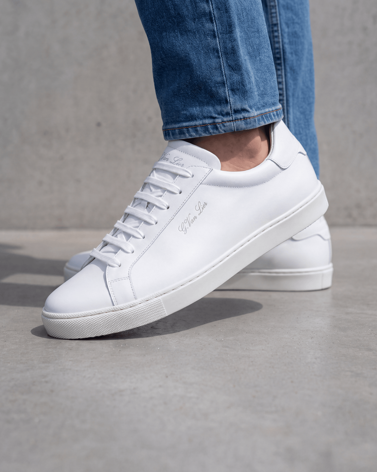 Wit gladleren Napoli sneaker – close-up van het paar op ruw beton