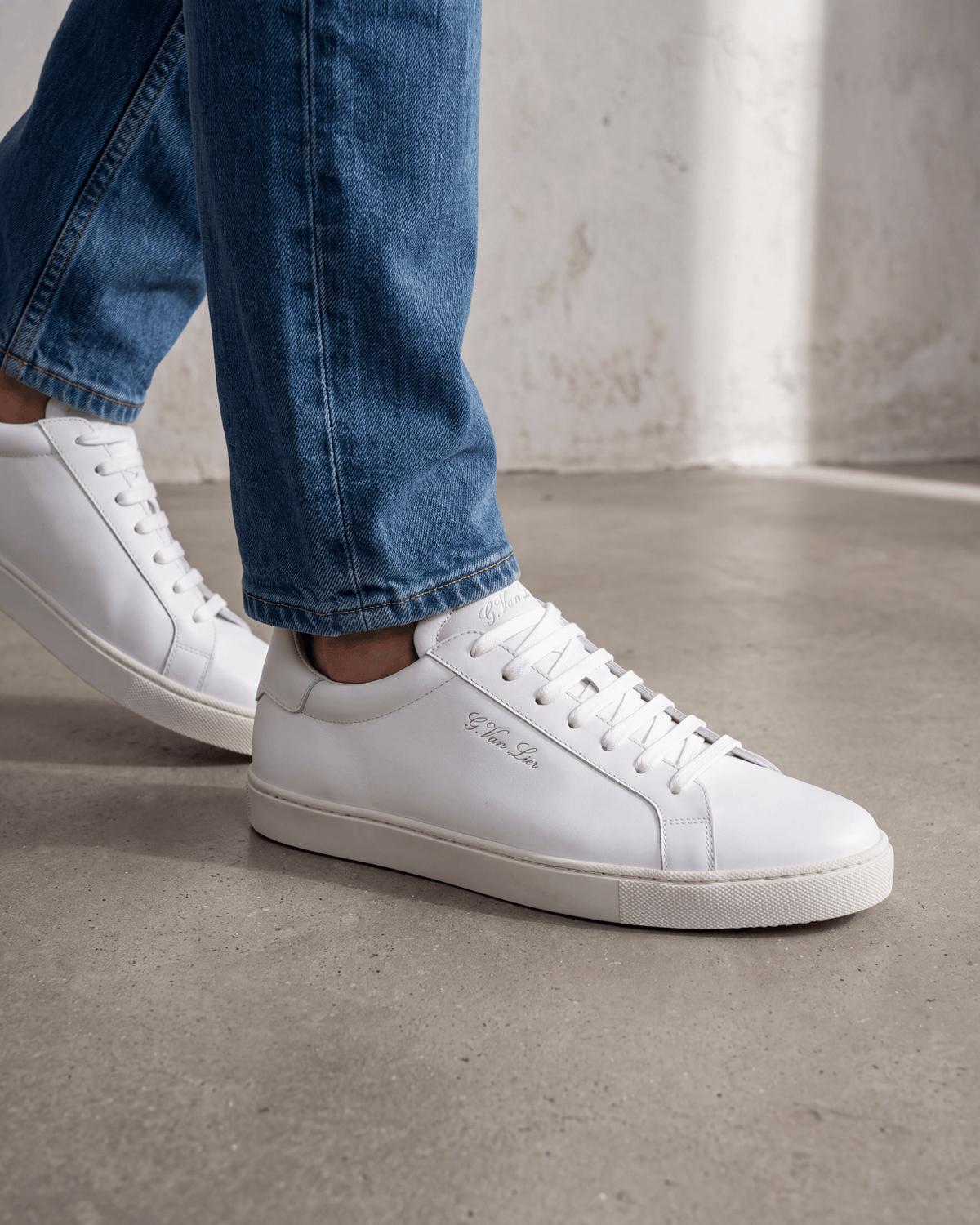 Wit gladleren Napoli sneaker – close-up van het paar op beton in een atelier