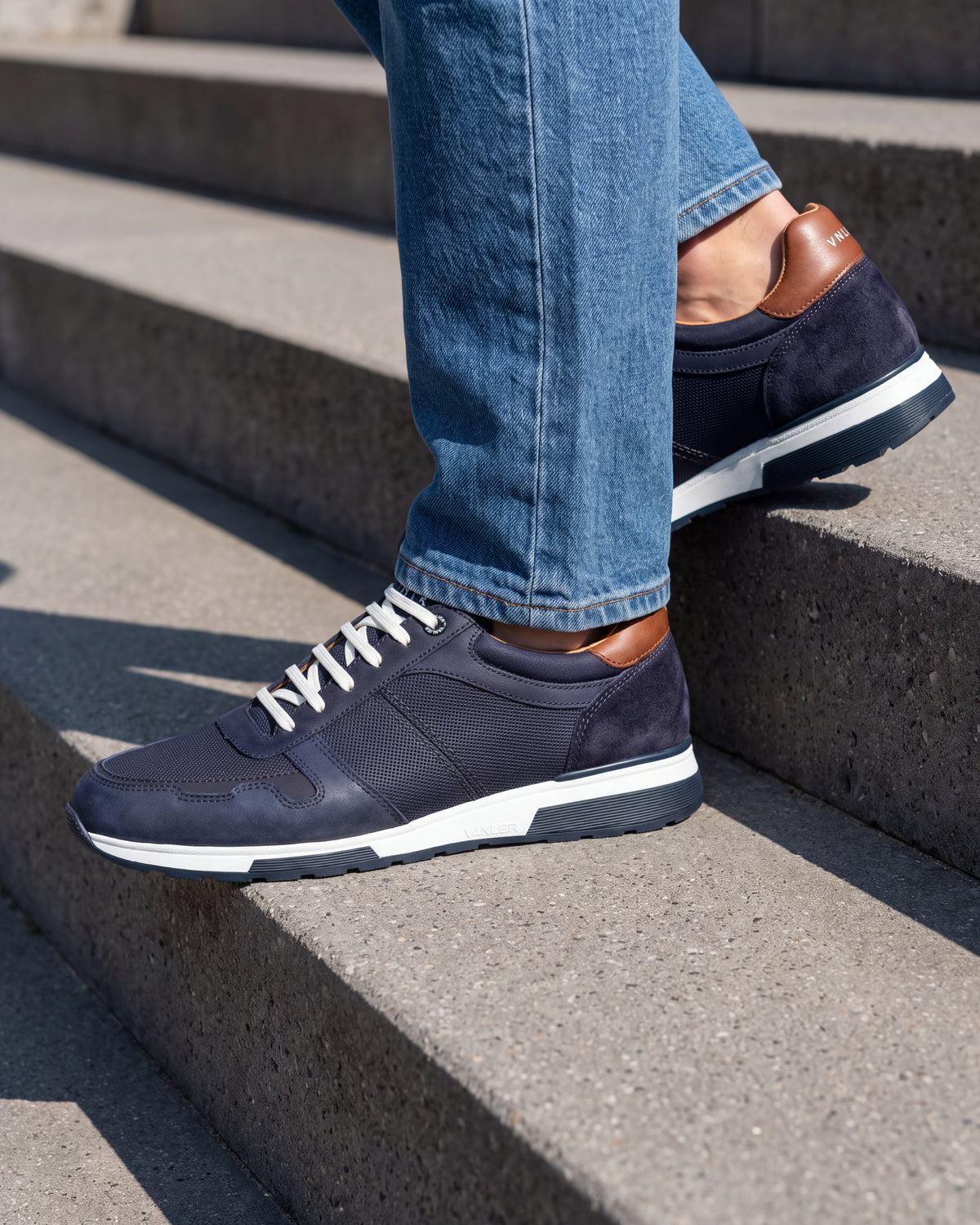 Navy blauw nubuck Positano sneaker – close-up van het paar op een ruwe betonnen vloer