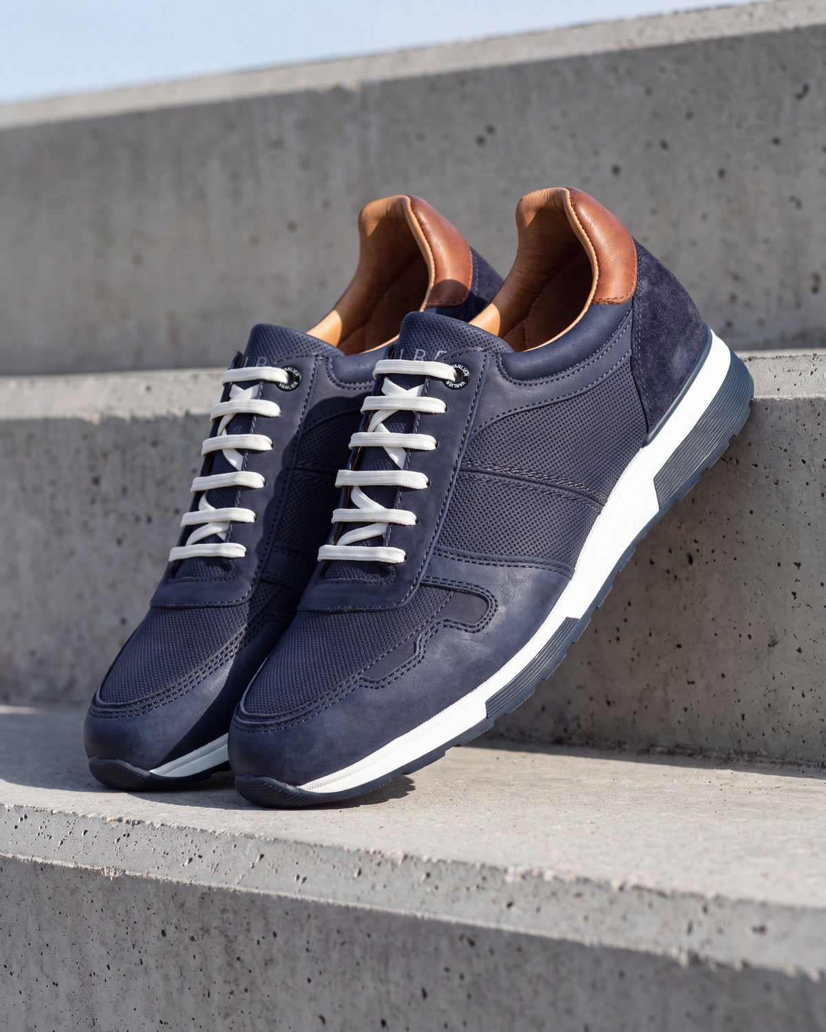 Navy blauw nubuck Positano sneaker – close-up van het paar op ruw beton