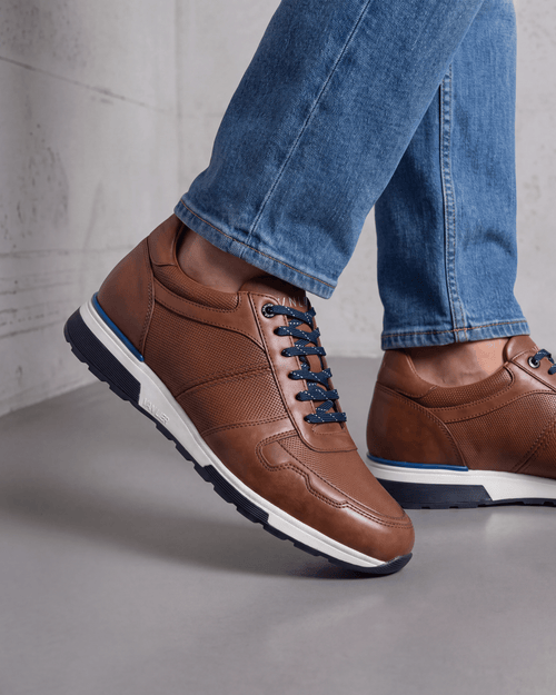 Cognac gladleren Positano sneaker – close-up van het paar op beton in een atelier
