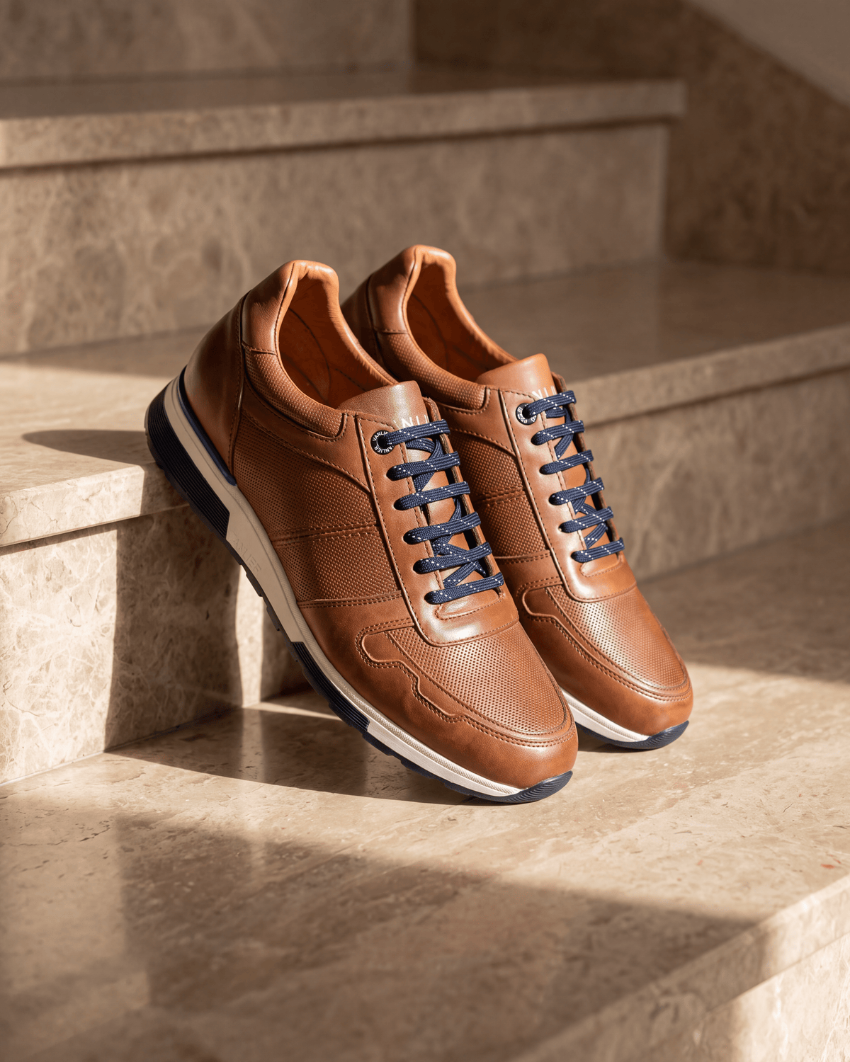 Cognac gladleren Positano sneaker – het paar op warm marmer