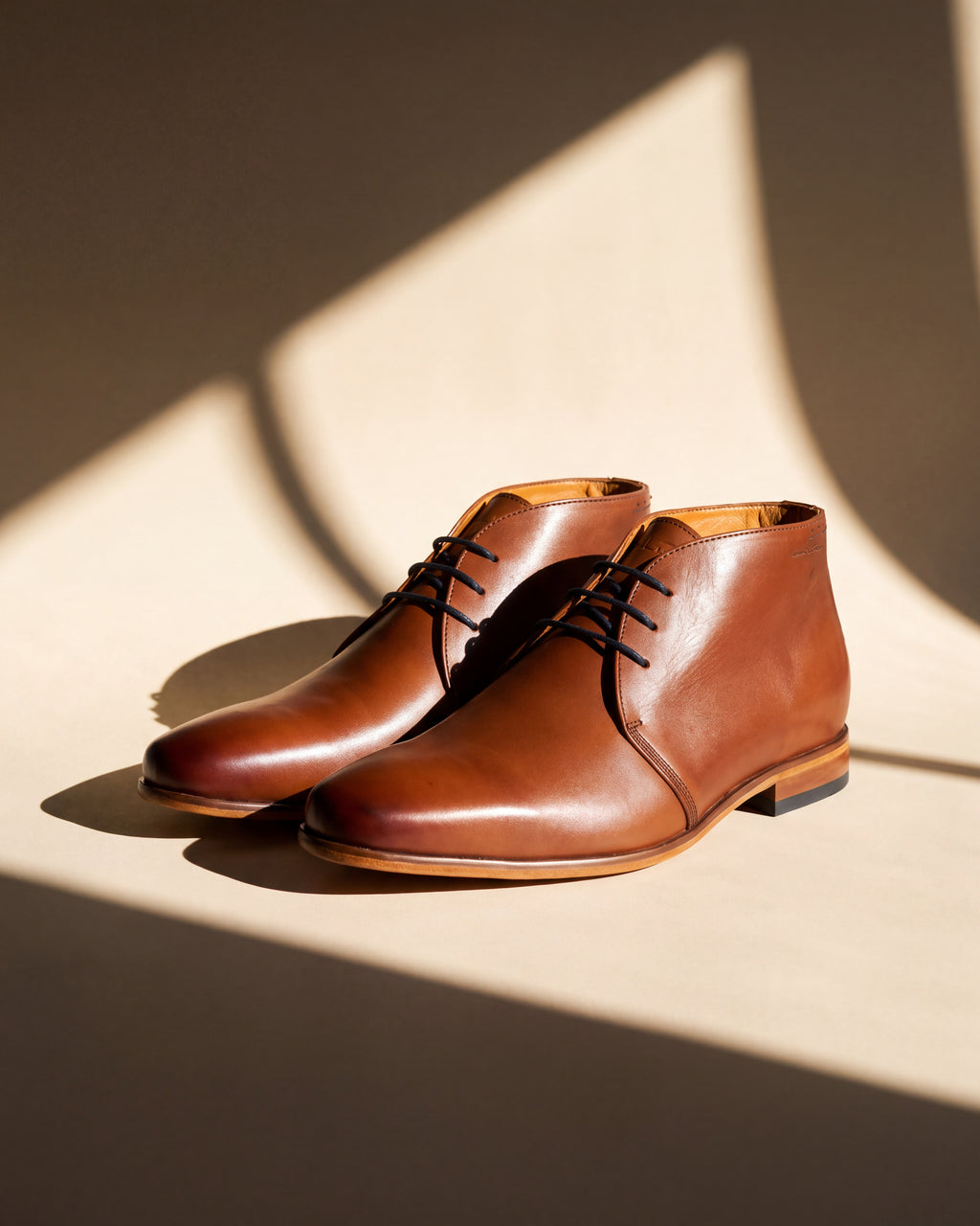 Cognac gladleren Rhodes halfhoge veterschoen – close-up van het paar met raamschaduw
