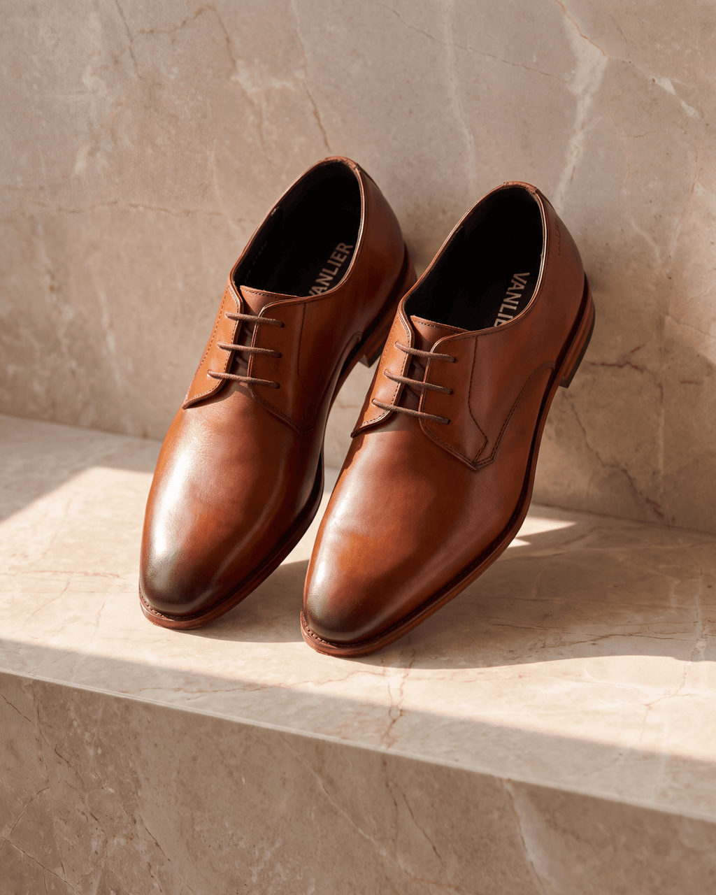 Cognac gladleren Madison veterschoen – het paar op warm marmer