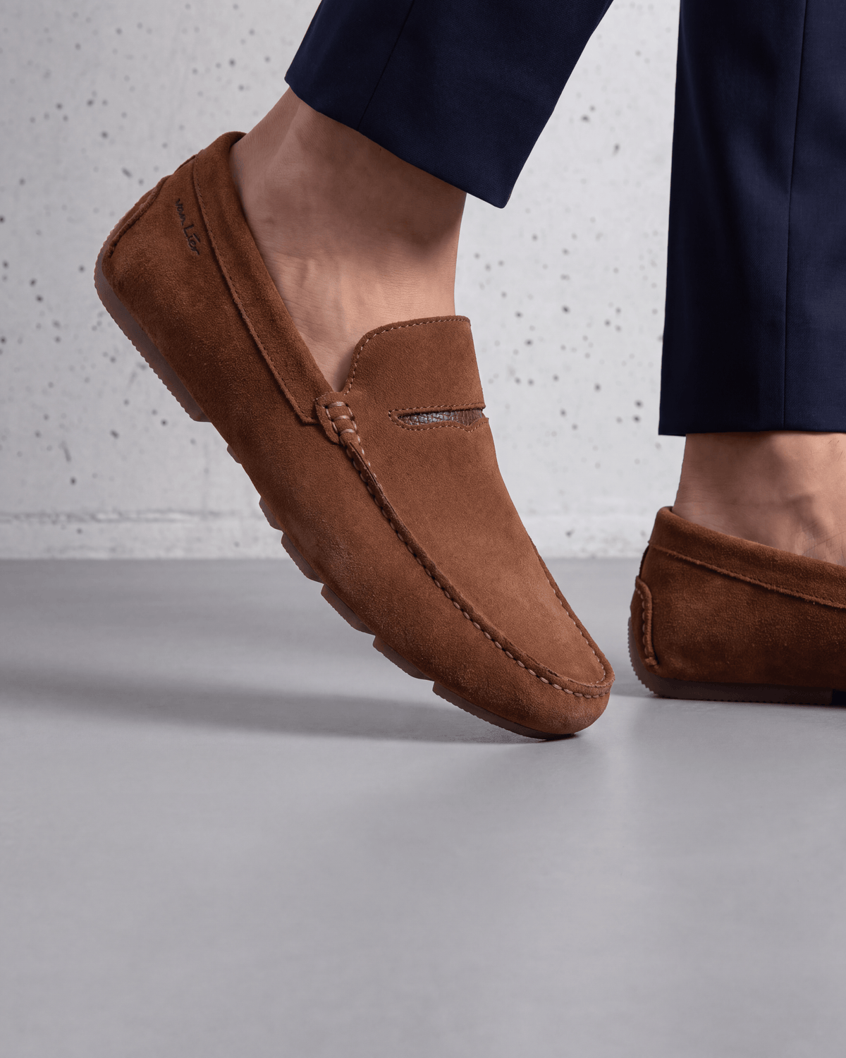Roest cognac suède Mocassin – close-up van het paar in een betonnen atelier