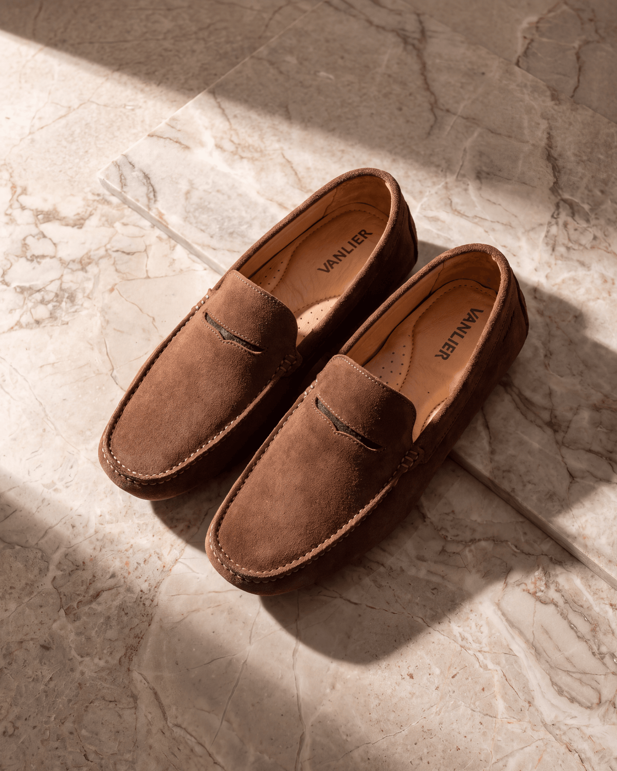 Roest cognac suède Mocassin – stilleven op warm marmer