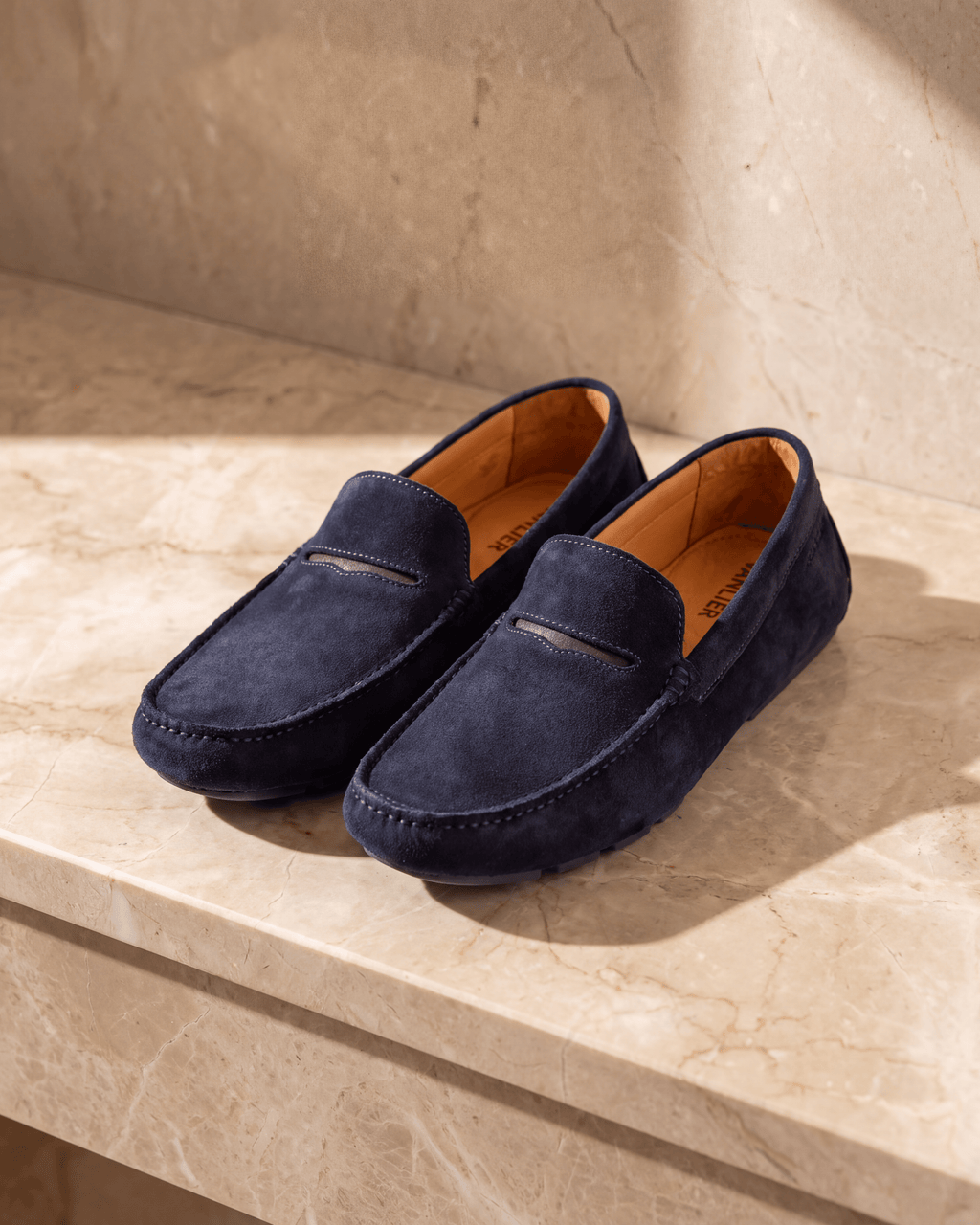 Navy blauw suède Mocassin – stilleven op warm marmer