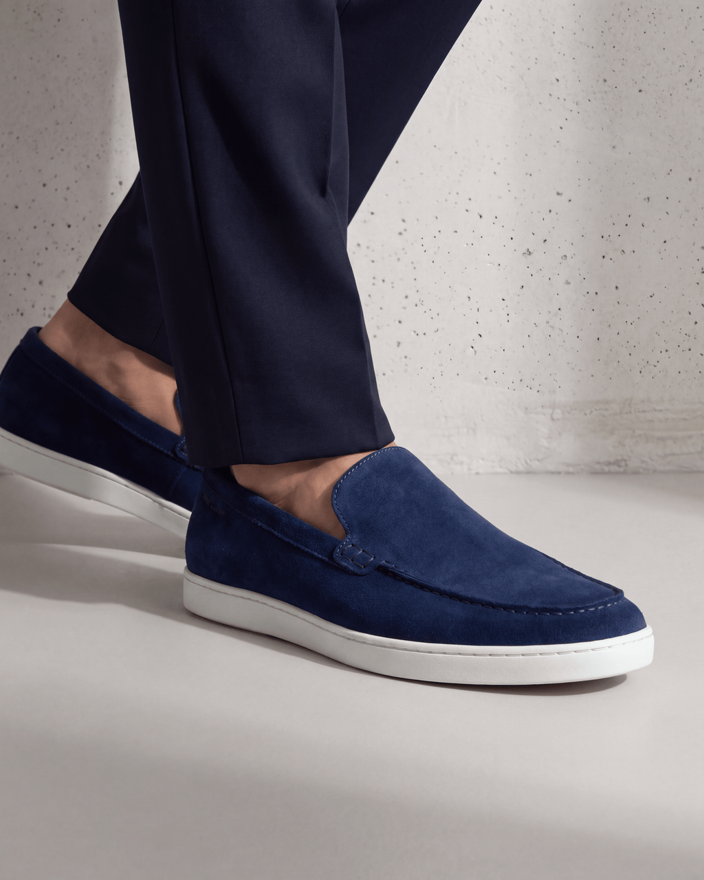 Blauw suède Lugano loafer – close-up van het paar op beton in een atelier