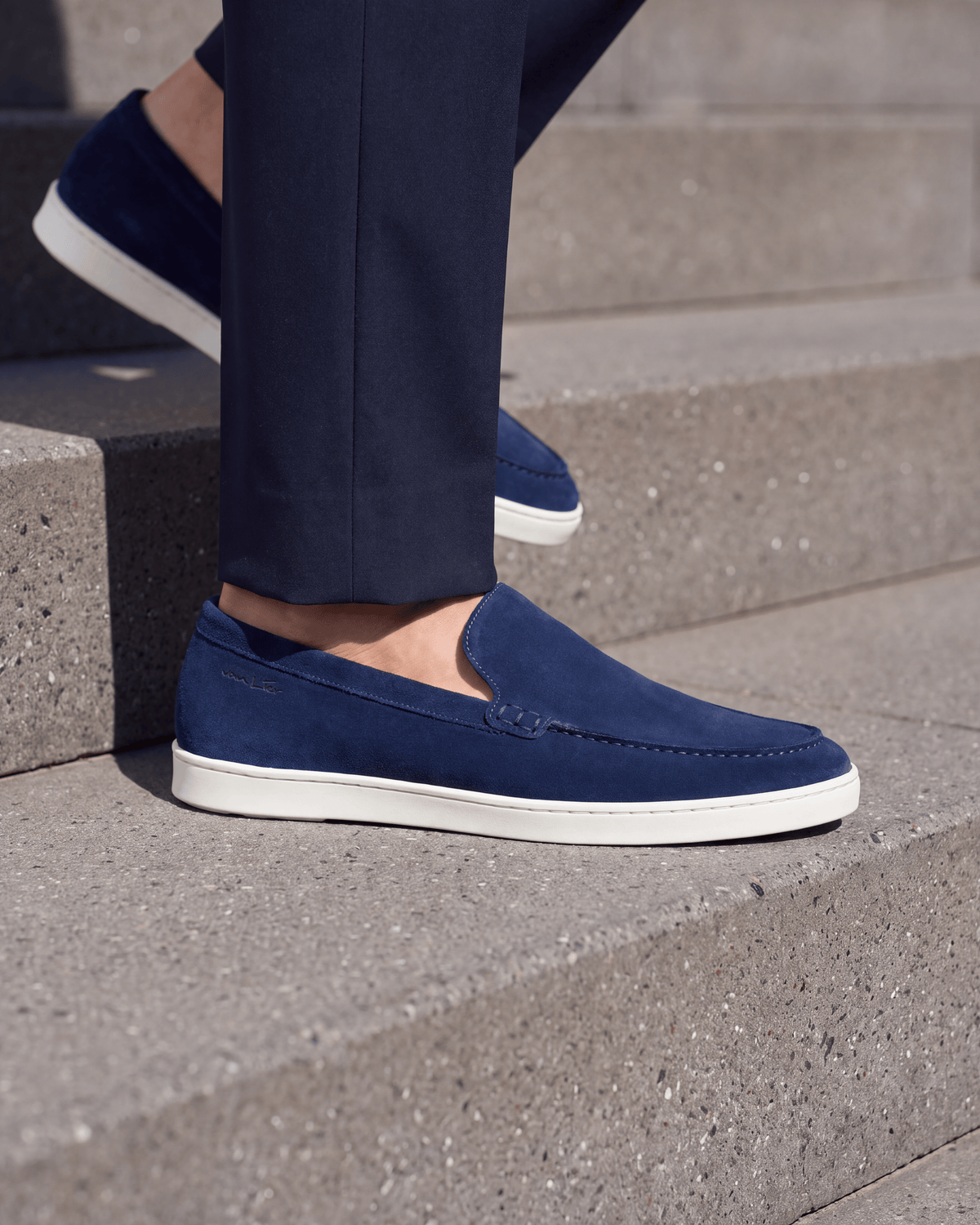 Blauw suède Lugano loafer – close-up van het paar op ruw beton
