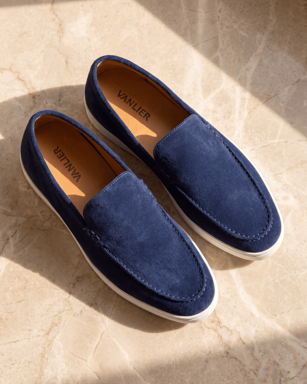 Blauw suède Lugano loafer – het paar op warm marmer