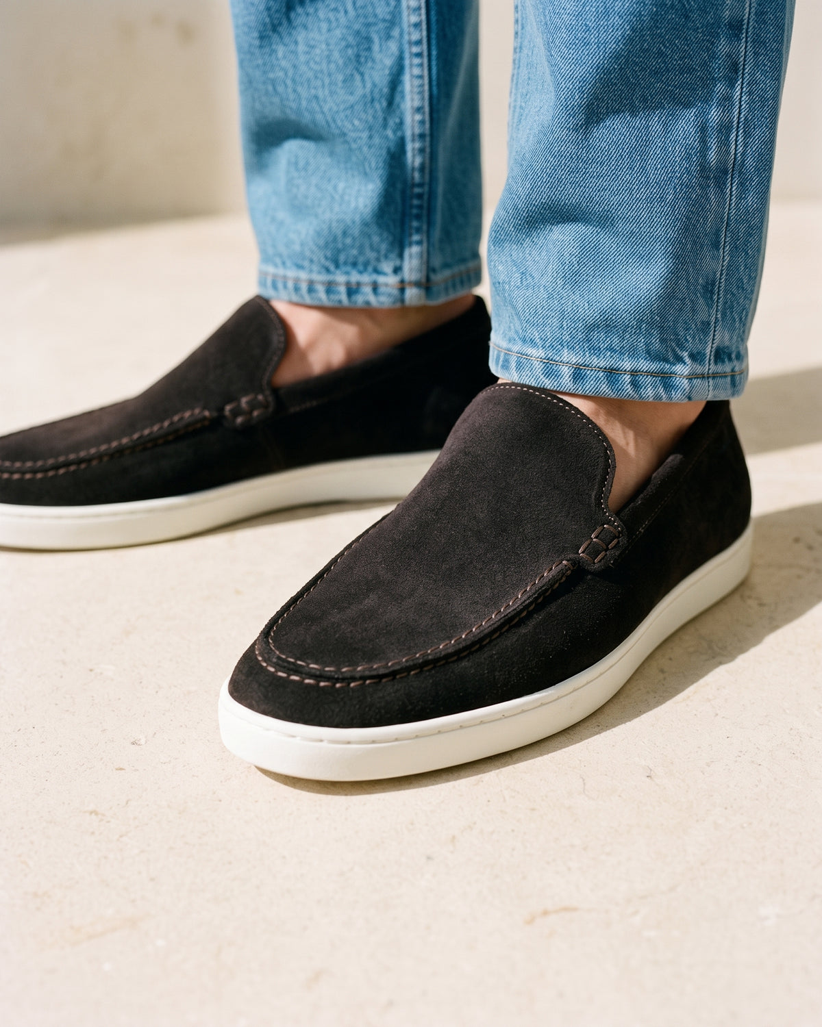 Testa di moro bruin suède Lugano loafer – close-up van het paar op een kalkstenen vloer, andere hoek