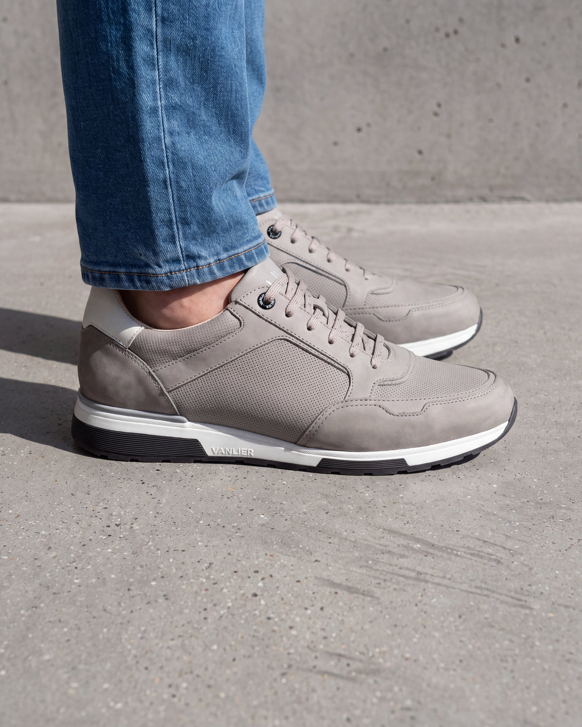 Lichtgrijs nubuck Positano sneaker – close-up van het paar op een ruwe betonnen vloer