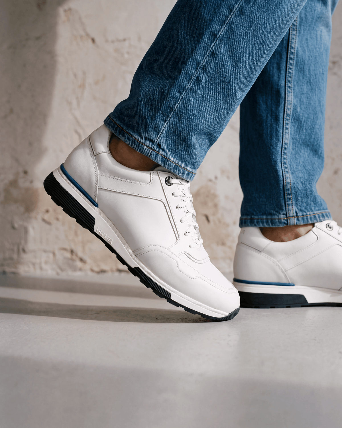 Wit gladleren Positano sneaker – close-up van het paar op beton in een atelier