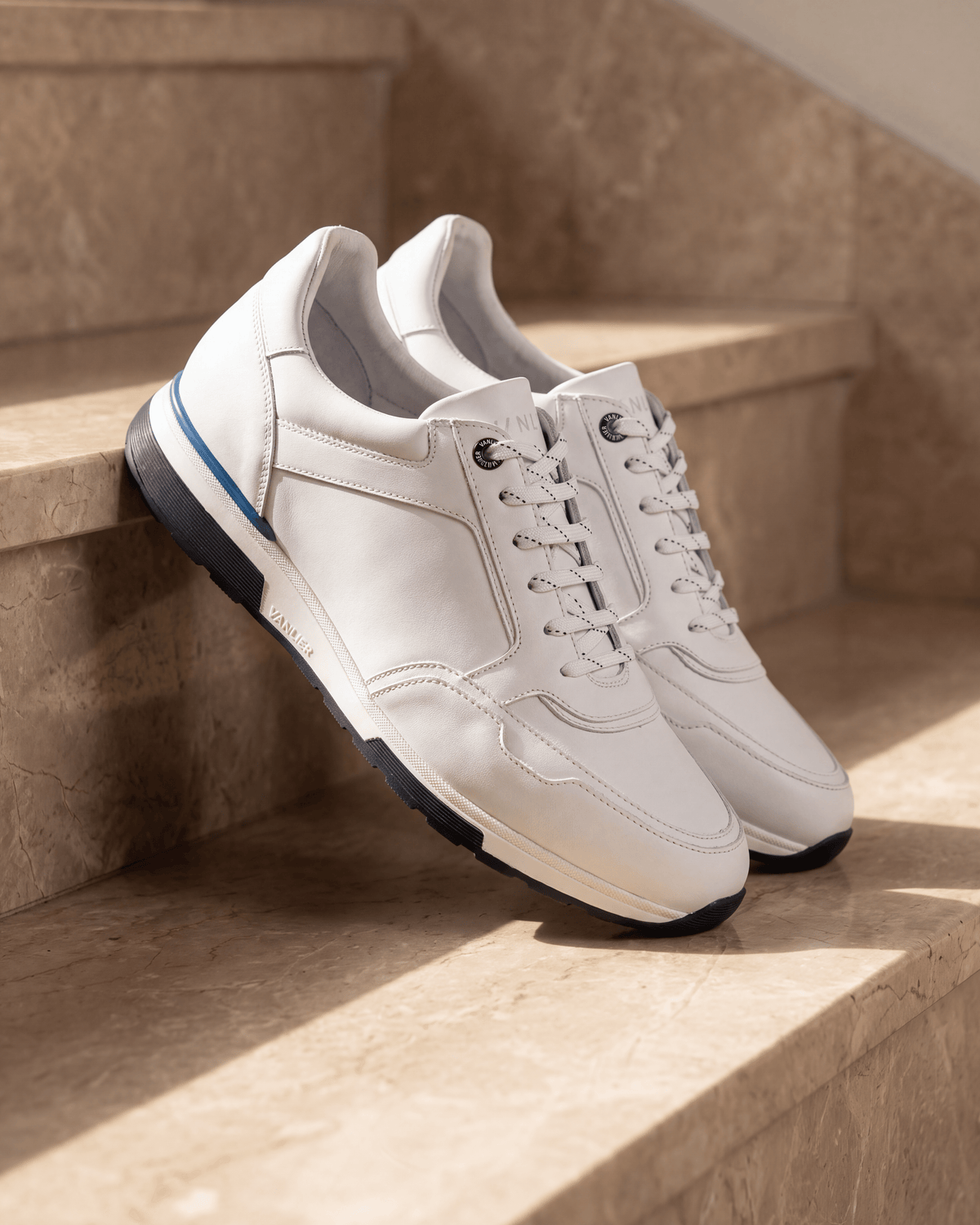 Wit gladleren Positano sneaker – het paar op warm marmer