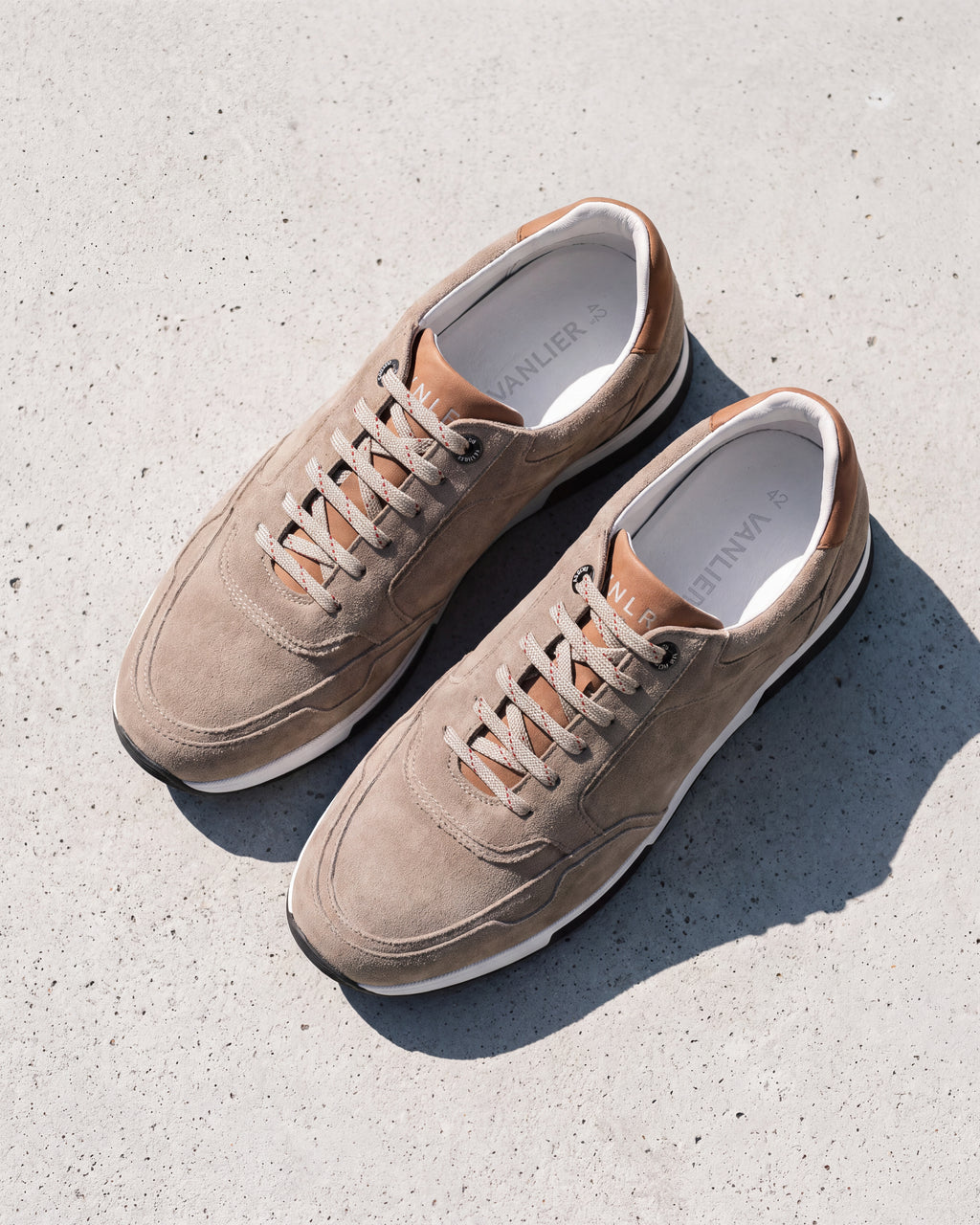 Taupe suède Positano sneaker – close-up van het paar op ruw beton