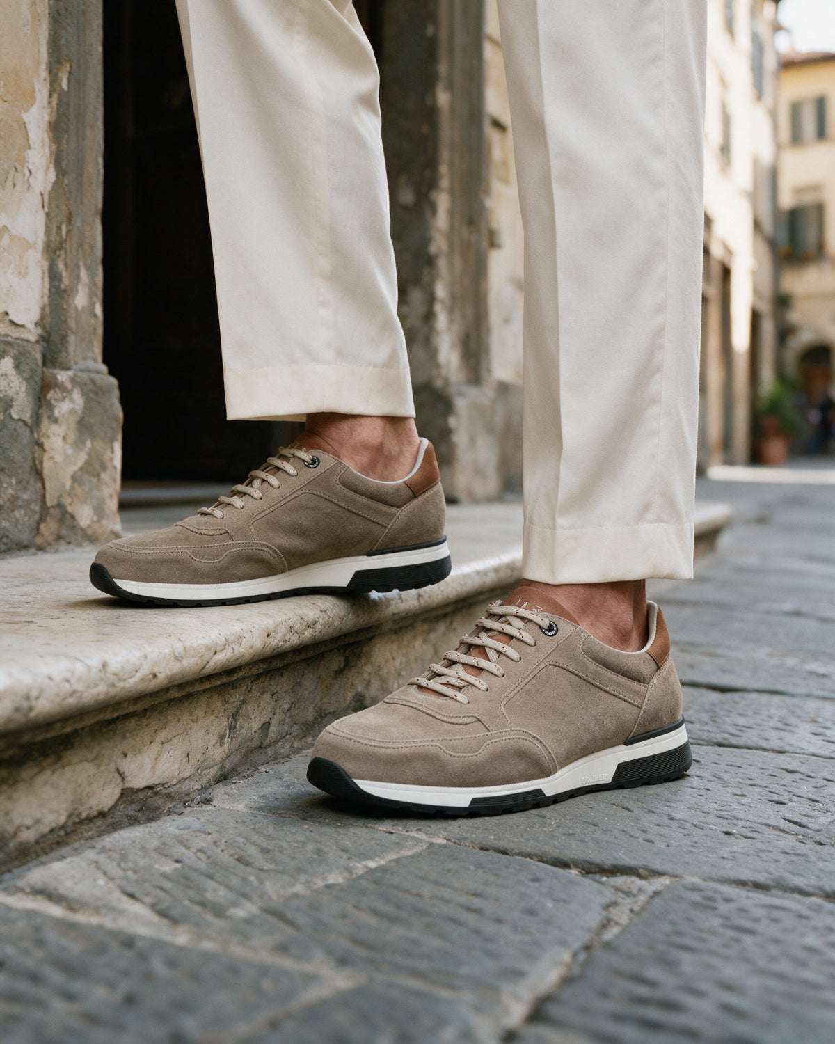 Taupe suède Positano sneaker – lifestyle close-up op steen
