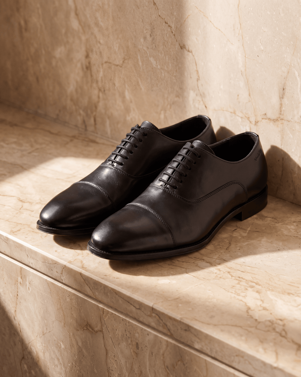 Zwart gladleren Madison veterschoen – het paar op warm marmer
