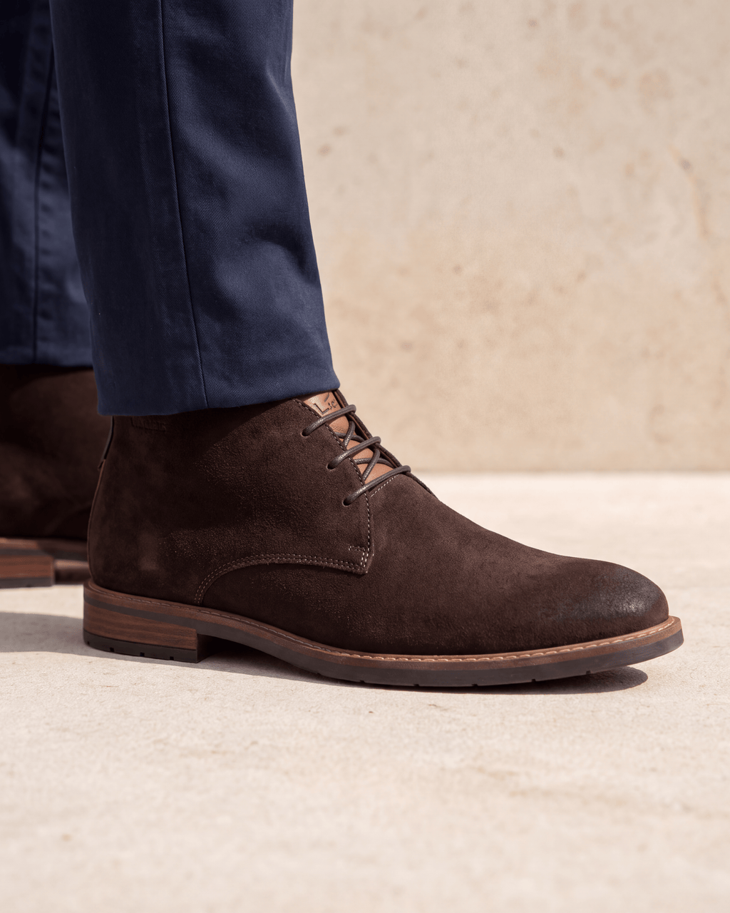 Donker bruin suède Boston boot – close-up van het paar op een kalkstenen vloer