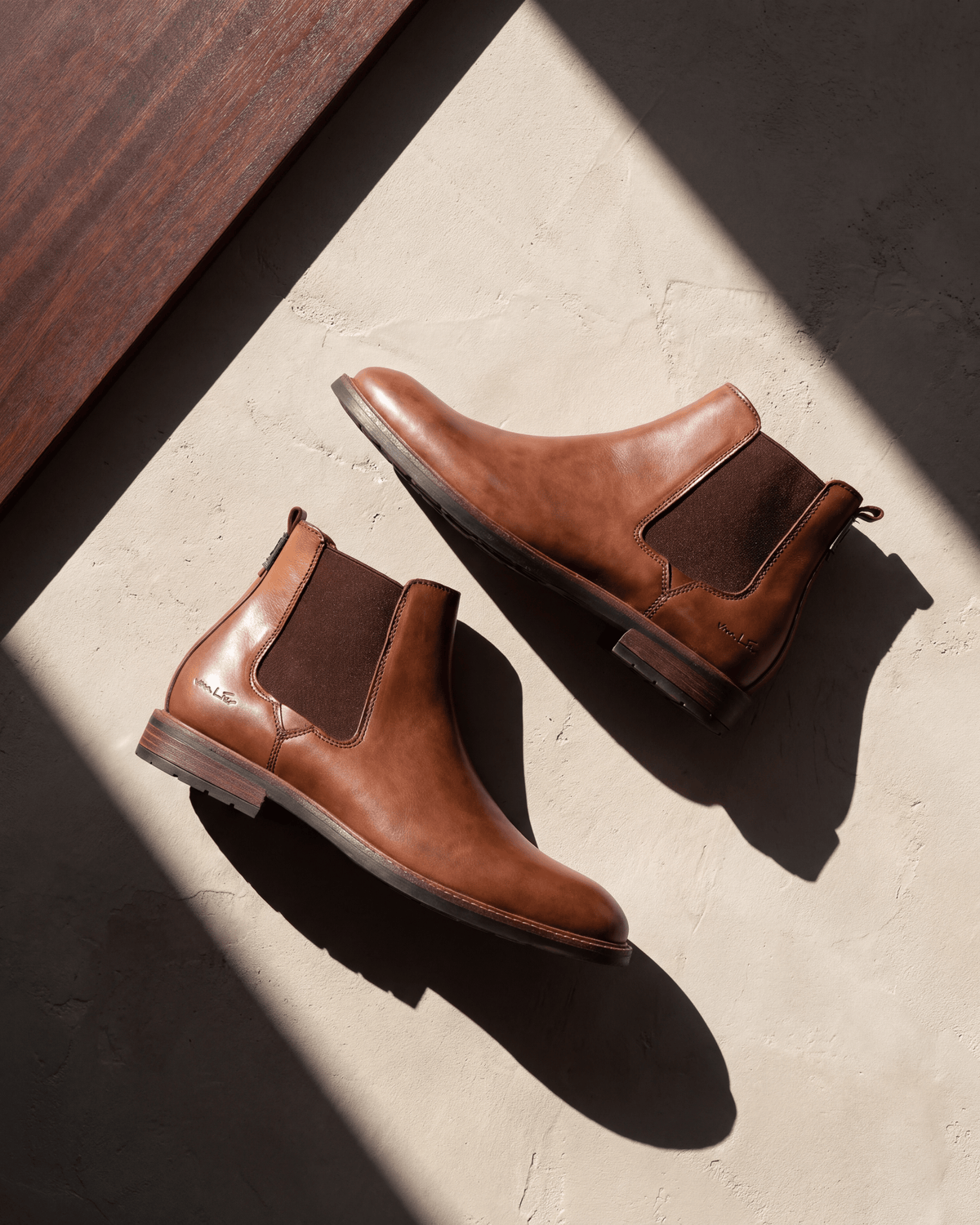 Cognac gladleren Boston chelsea boot – het paar op hout en pleisterwerk