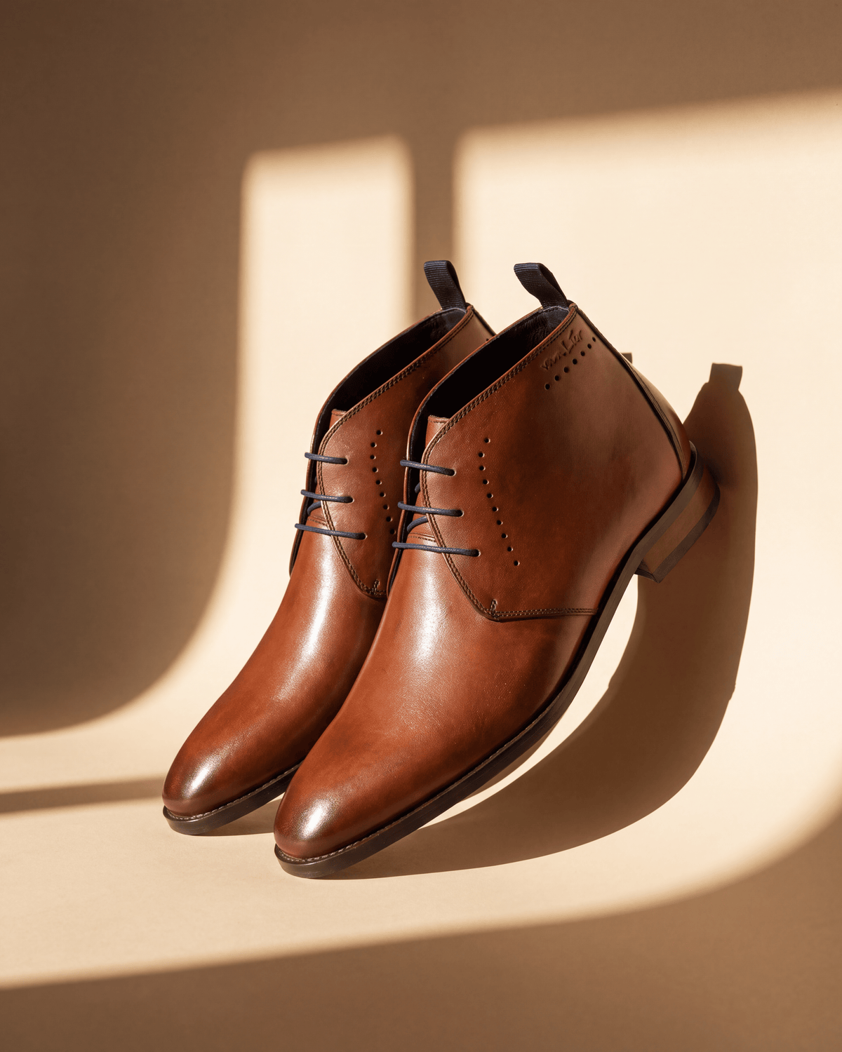 Cognac gladleren Bregenz halfhoge veterschoen – detail bij een raam met schaduw