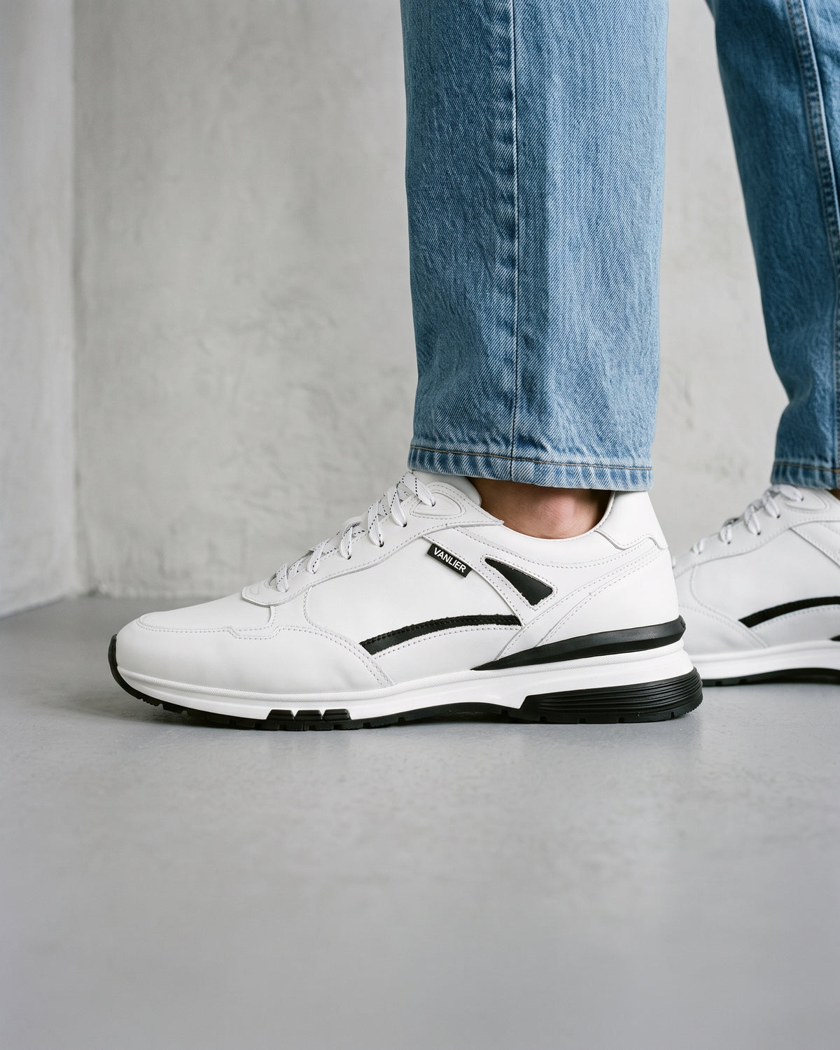 Wit gladleren Veneto sneaker – close-up van het paar in een betonnen atelier