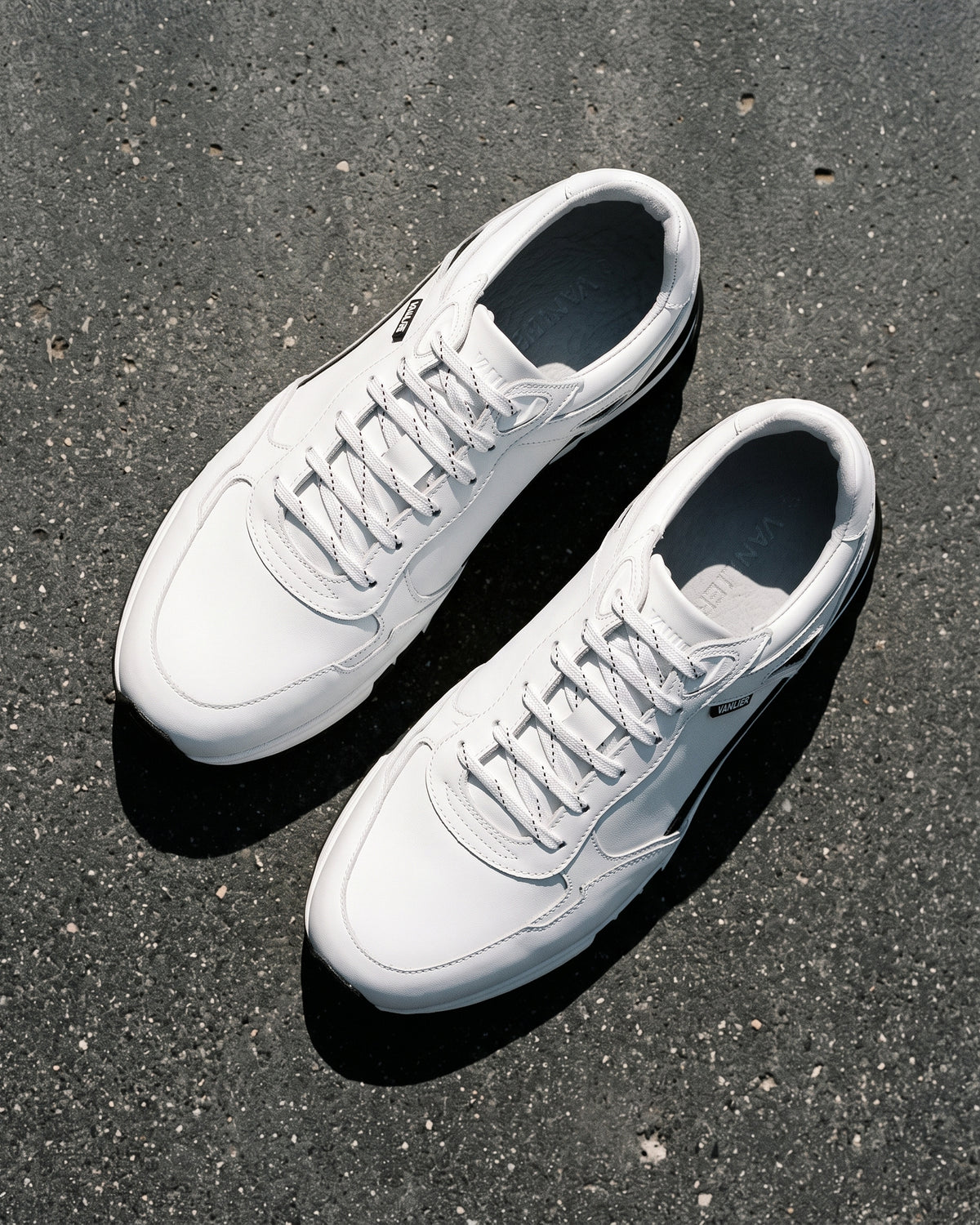 Wit gladleren Veneto sneaker – paar op ruw beton, andere hoek