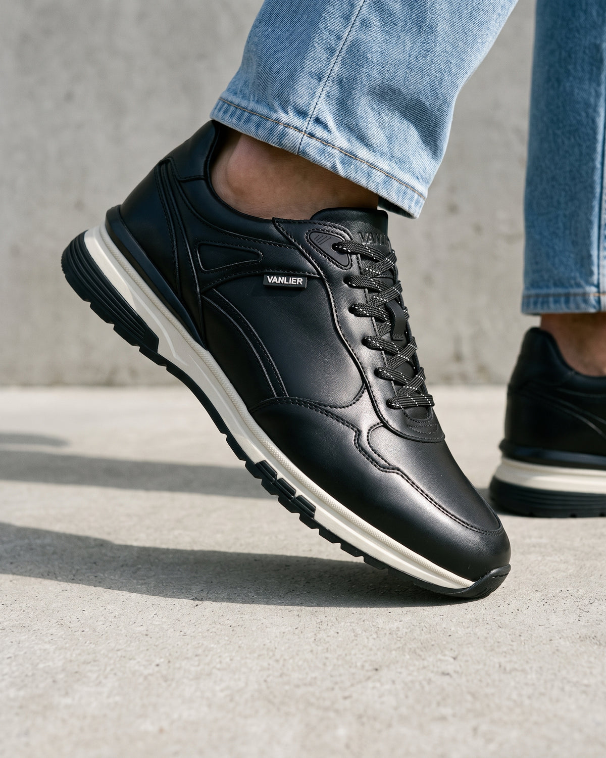Zwart gladleren Veneto sneaker – close-up van het paar op een betonnen vloer